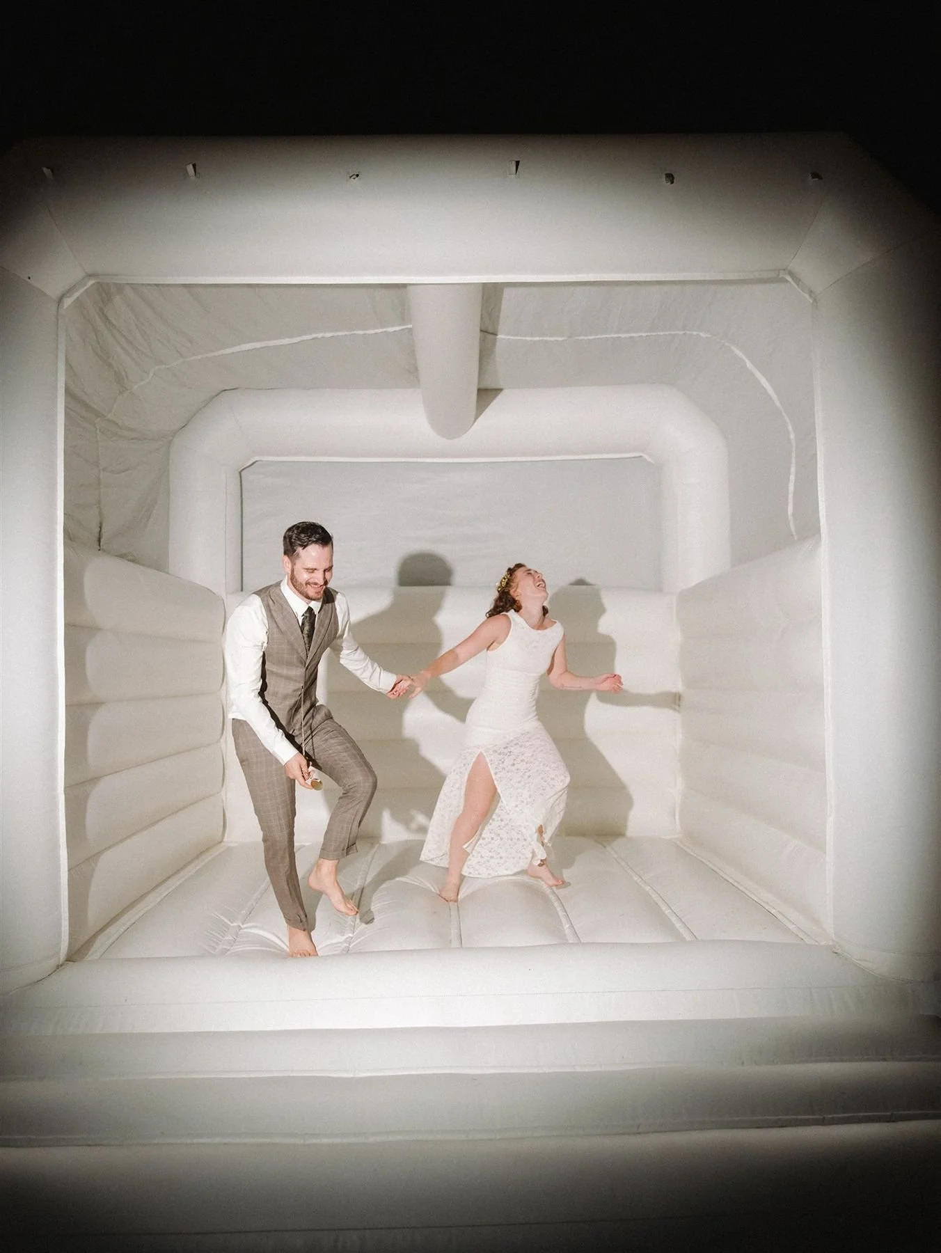 gen z wedding humor during bride and groom bounce house moment laughing and playful