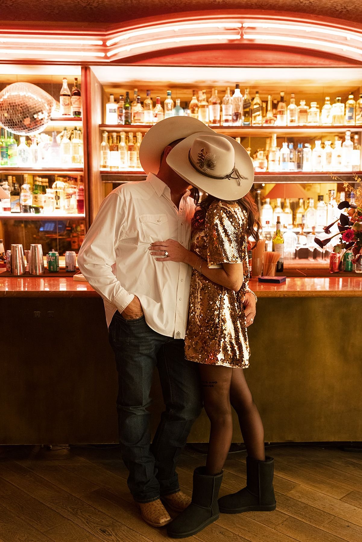 Speakeasy bar after party designed by Kelly wearstler at Austin propers quill bar with brides after party look in gold sequin mini dress, black tights and black Uggs with their cowboy hats
