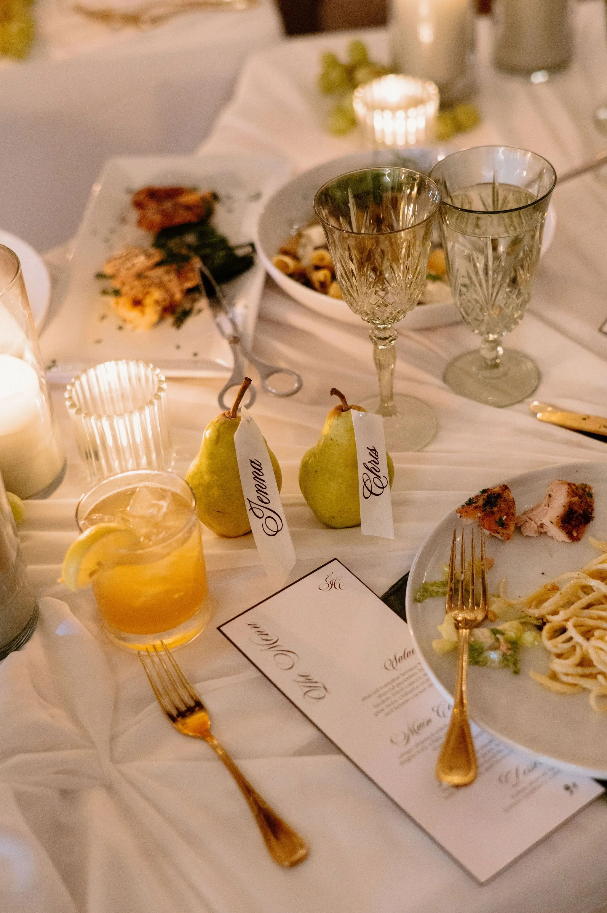 Wedding dinner table with custom pear place cards, cocktails, and crystal glassware — intimate guest-focused experience