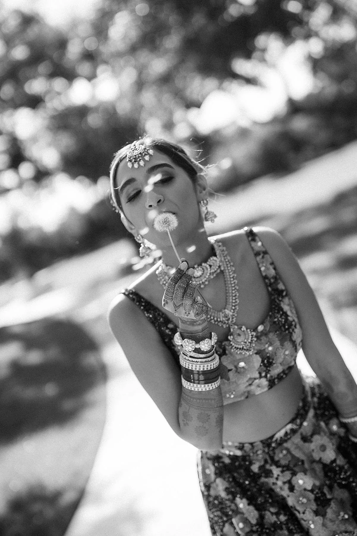 Indian bride wearing couture traditional sabyasachi bridal gown and blowing a dandelion flower in black and white - bridal portrait epoch co