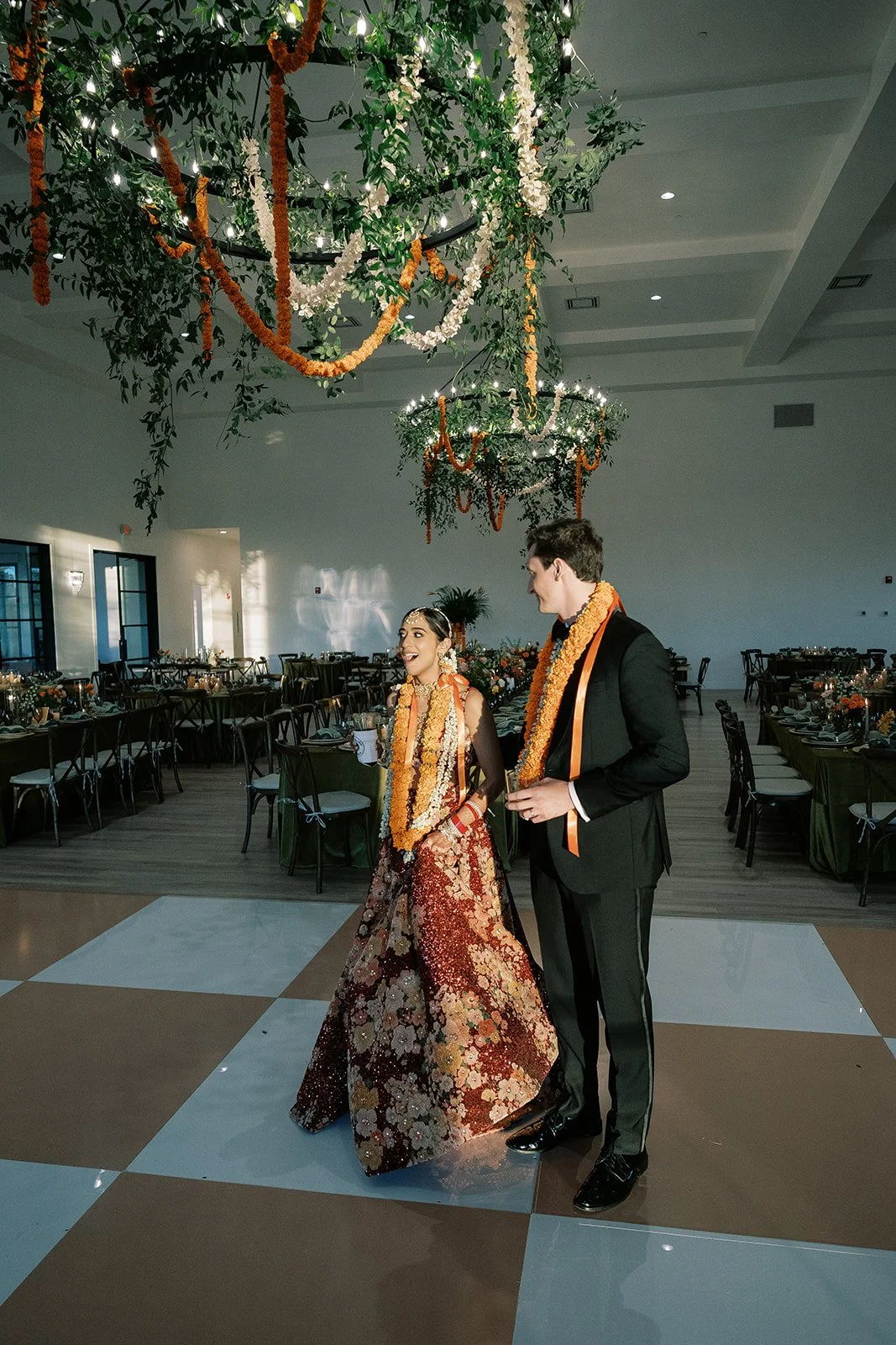 Checkered dance floor and chandeliers draped in greenery and marigolds at Austin Wedding Venue The Arlo for a Hindu fusion wedding