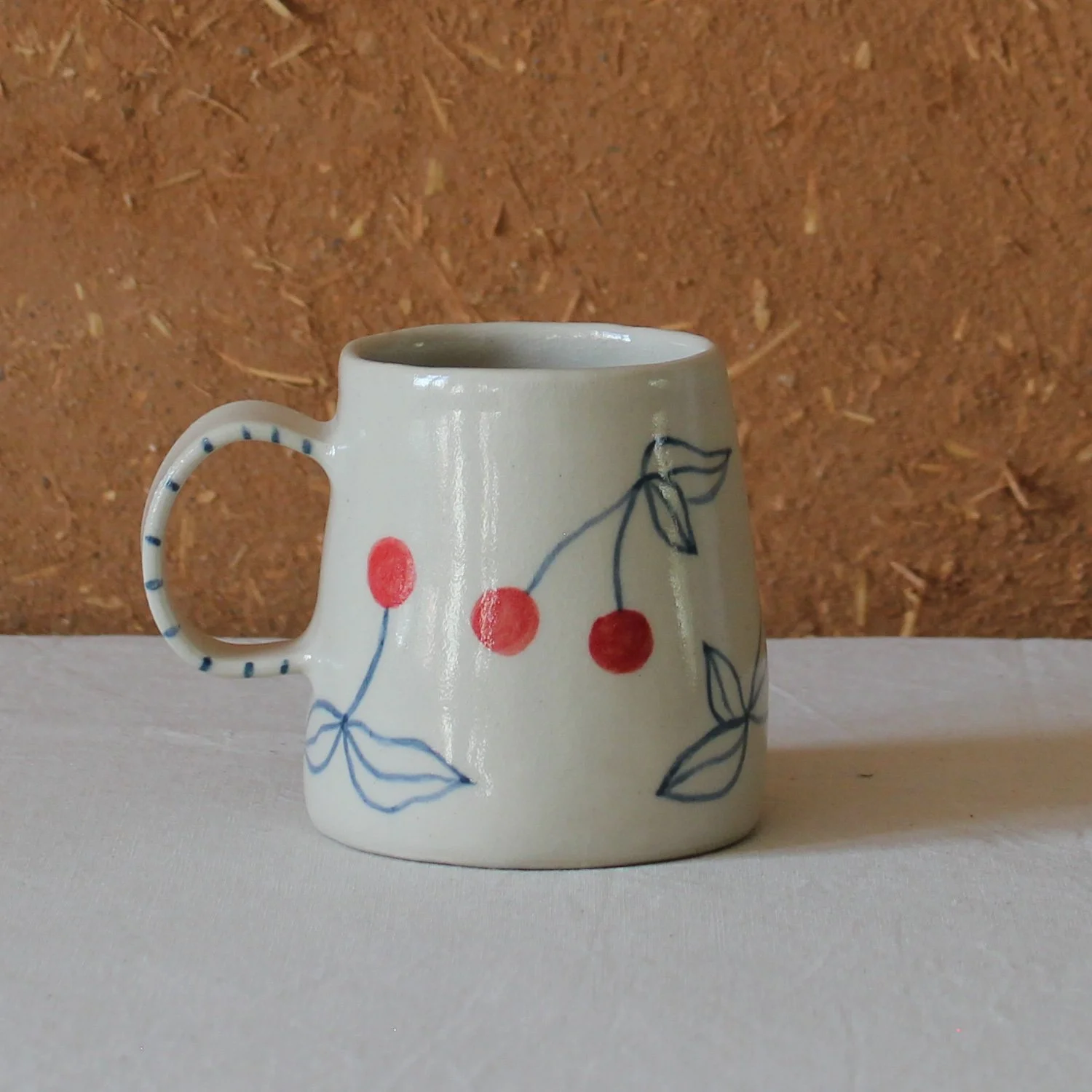  Vue de profil d’une tasse à anse conique à base large, en grès, motif Cerises, création artisanale à Nanteau-sur-Lunain 
