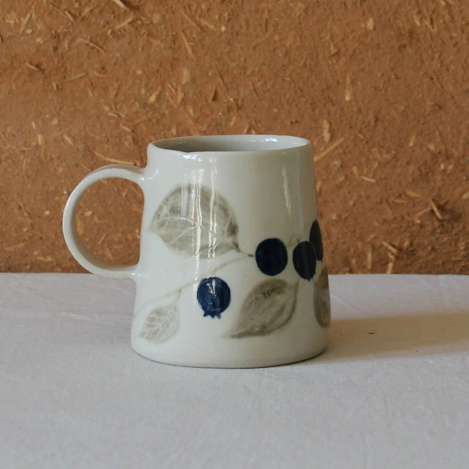  Vue de profil d’une tasse à anse conique à base large, en grès, motif Myrtille, création artisanale à Nanteau-sur-Lunain 