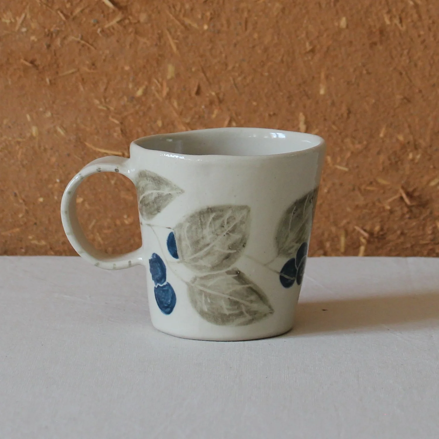  Vue de profil d’une tasse à anse conique à base étroite, en grès, motif Myrtille, création artisanale à Nanteau-sur-Lunain 