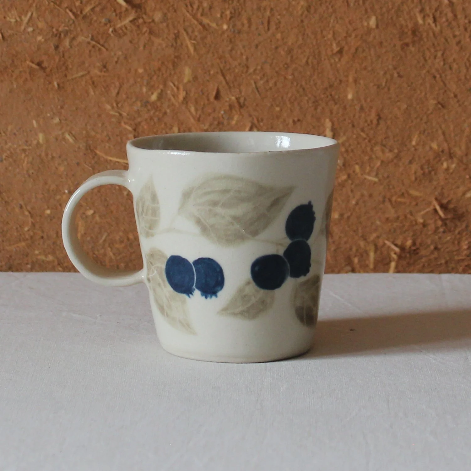  Vue de profil d’une tasse à anse conique à base étroite, en grès, motif Myrtille, création artisanale à Nanteau-sur-Lunain 