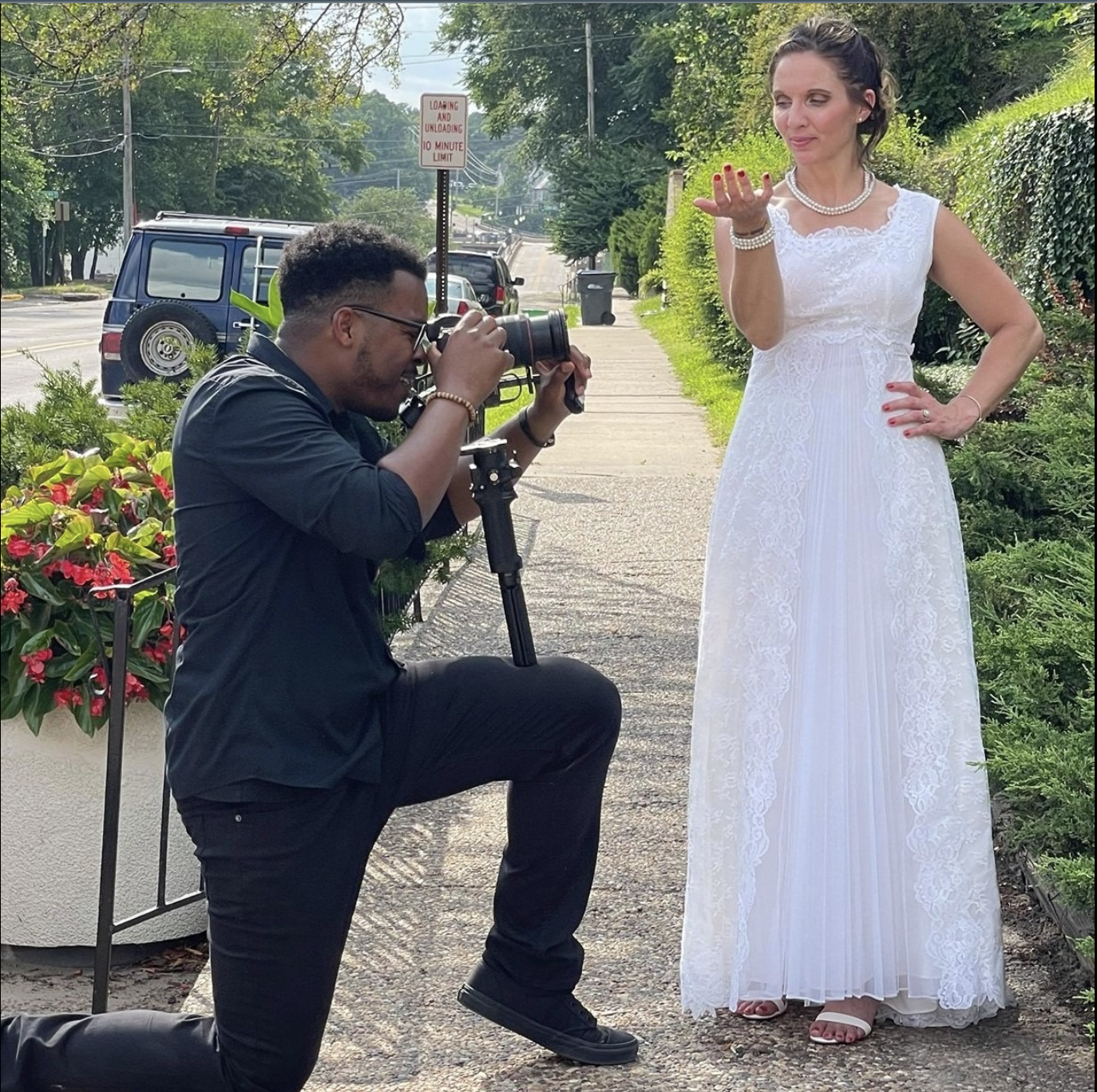 Photographer taking a picture of a woman in a white dress outdoors.