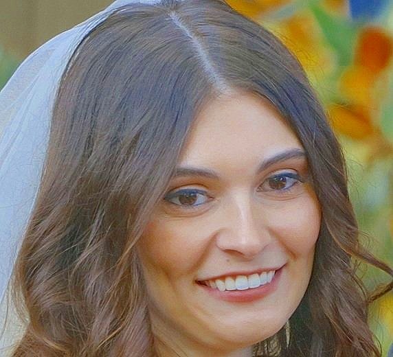 Smiling bride with veil and long brown hair in front of colorful background