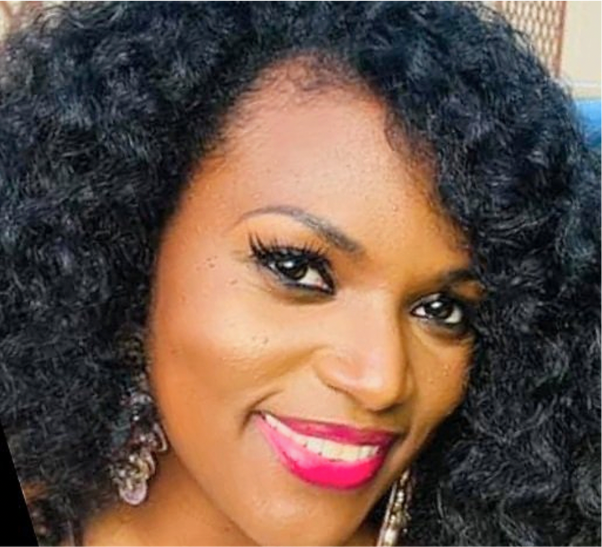 Smiling woman with curly black hair and pink lipstick.