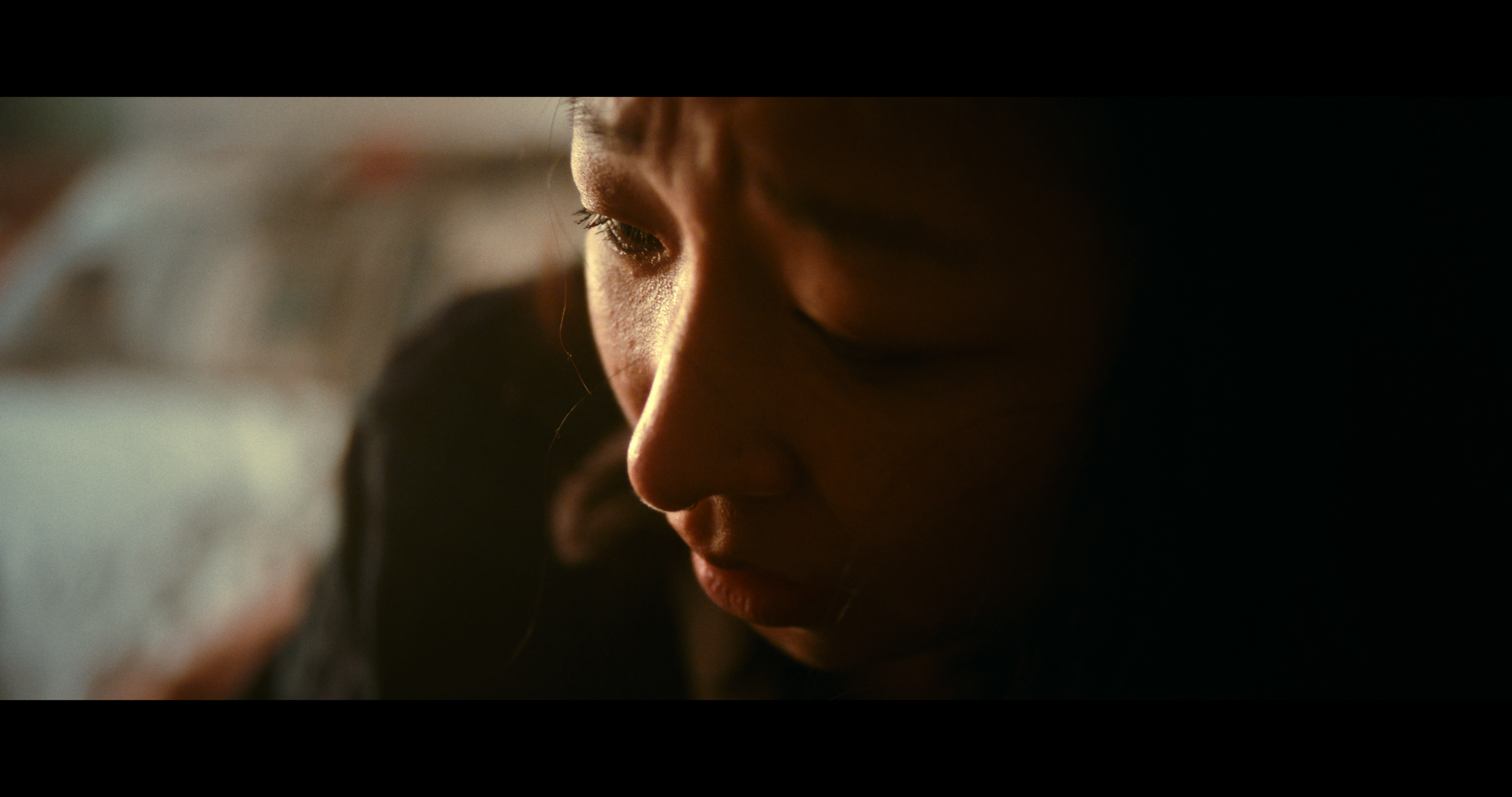 A close-up of a person's face in soft lighting, with eyes closed, appearing introspective.