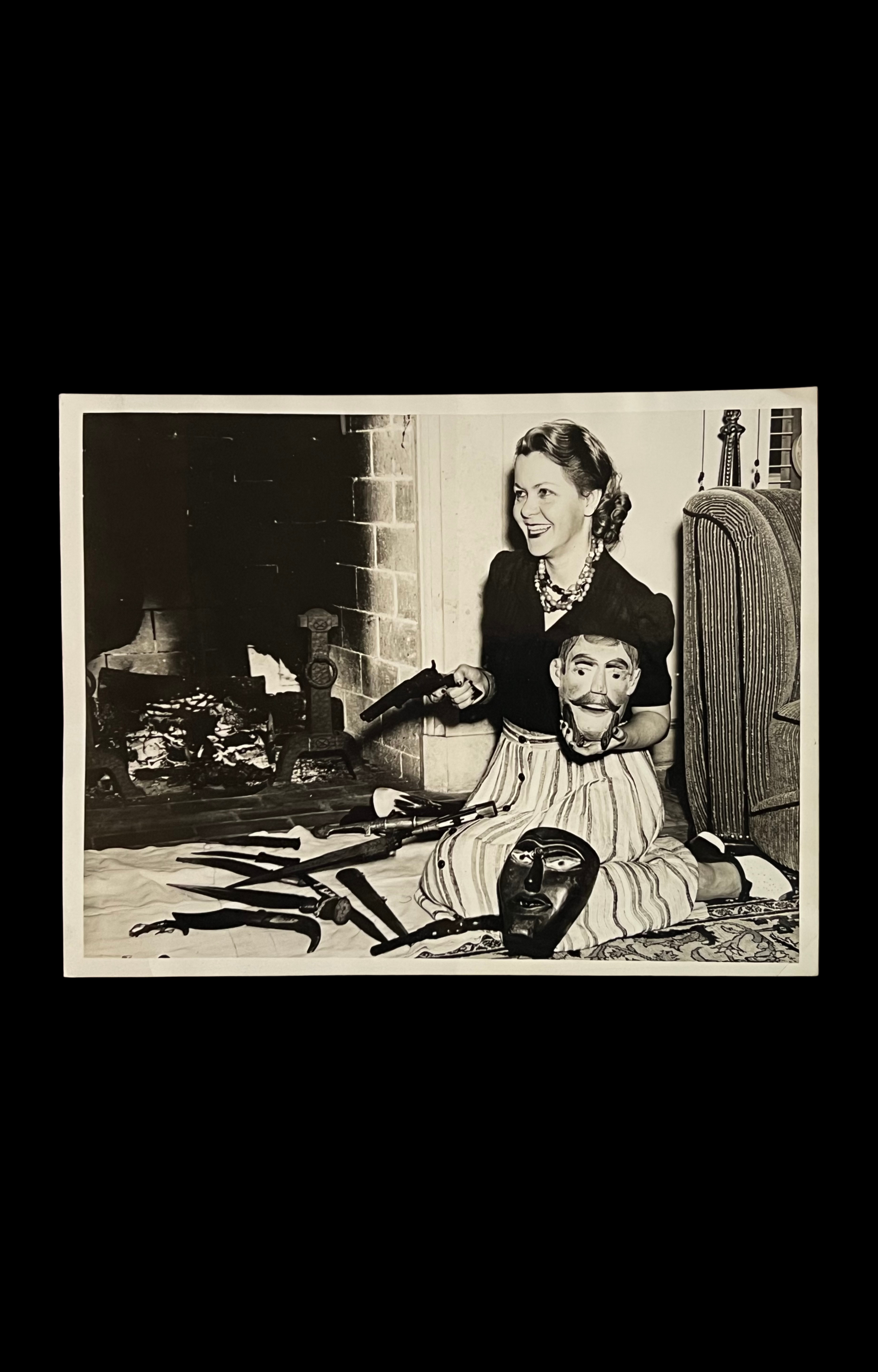 "Mrs. John M. Murrell", Photograph of Grinning Woman by Fireplace with Weapons and Masks, c. 1950