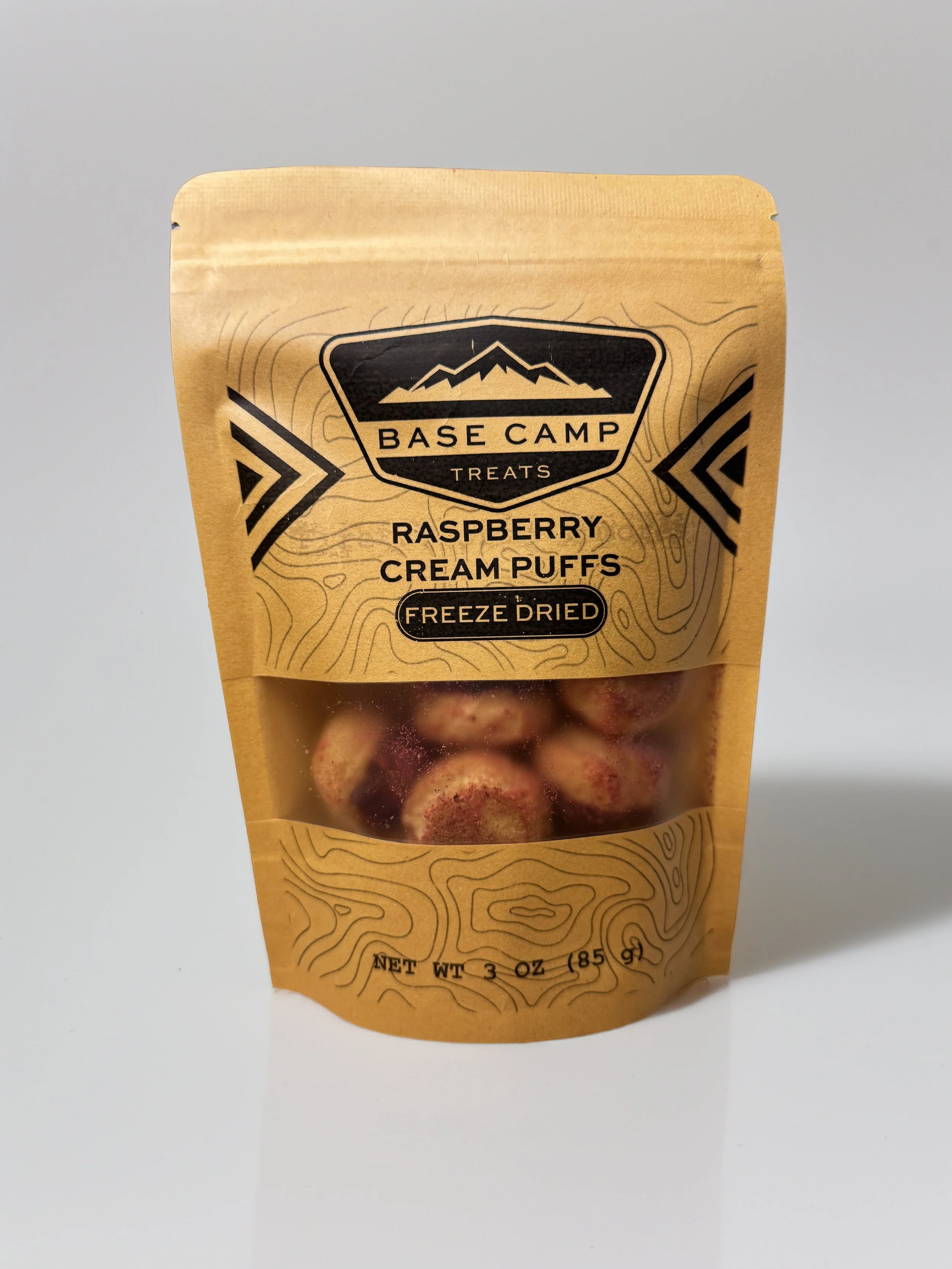 Base Camp Treats Freeze Dried Raspberry Cream Puffs in kraft stand-up pouch with raspberry-coated cream puffs visible through clear window