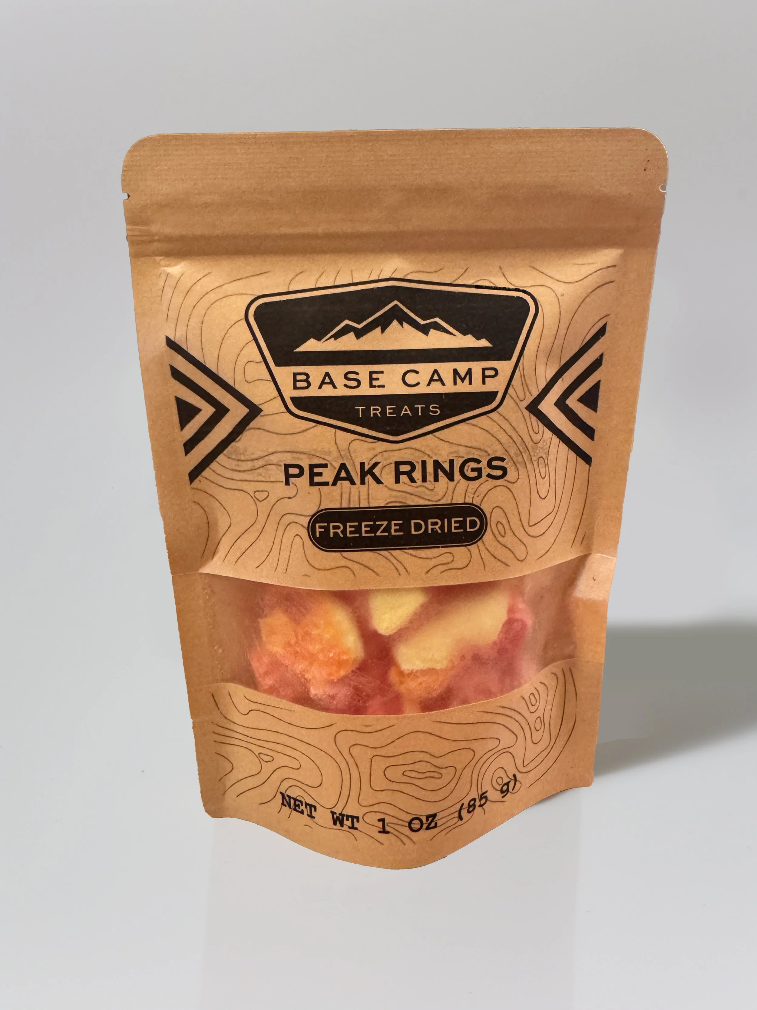 Base Camp Treats Freeze Dried Peach Rings in kraft stand-up pouch with crunchy peach gummy candy visible through clear window.