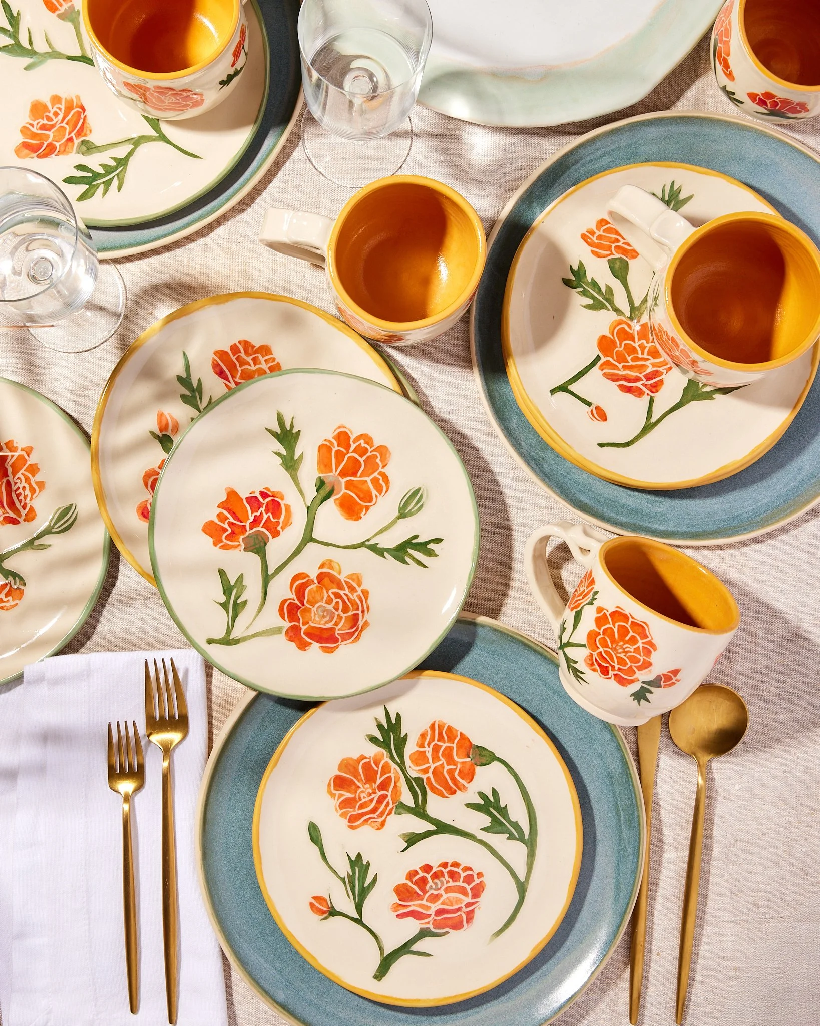 Overhead image of a tablescape of handmade, handpainted, and hand-carved pottery in a marigold motif.