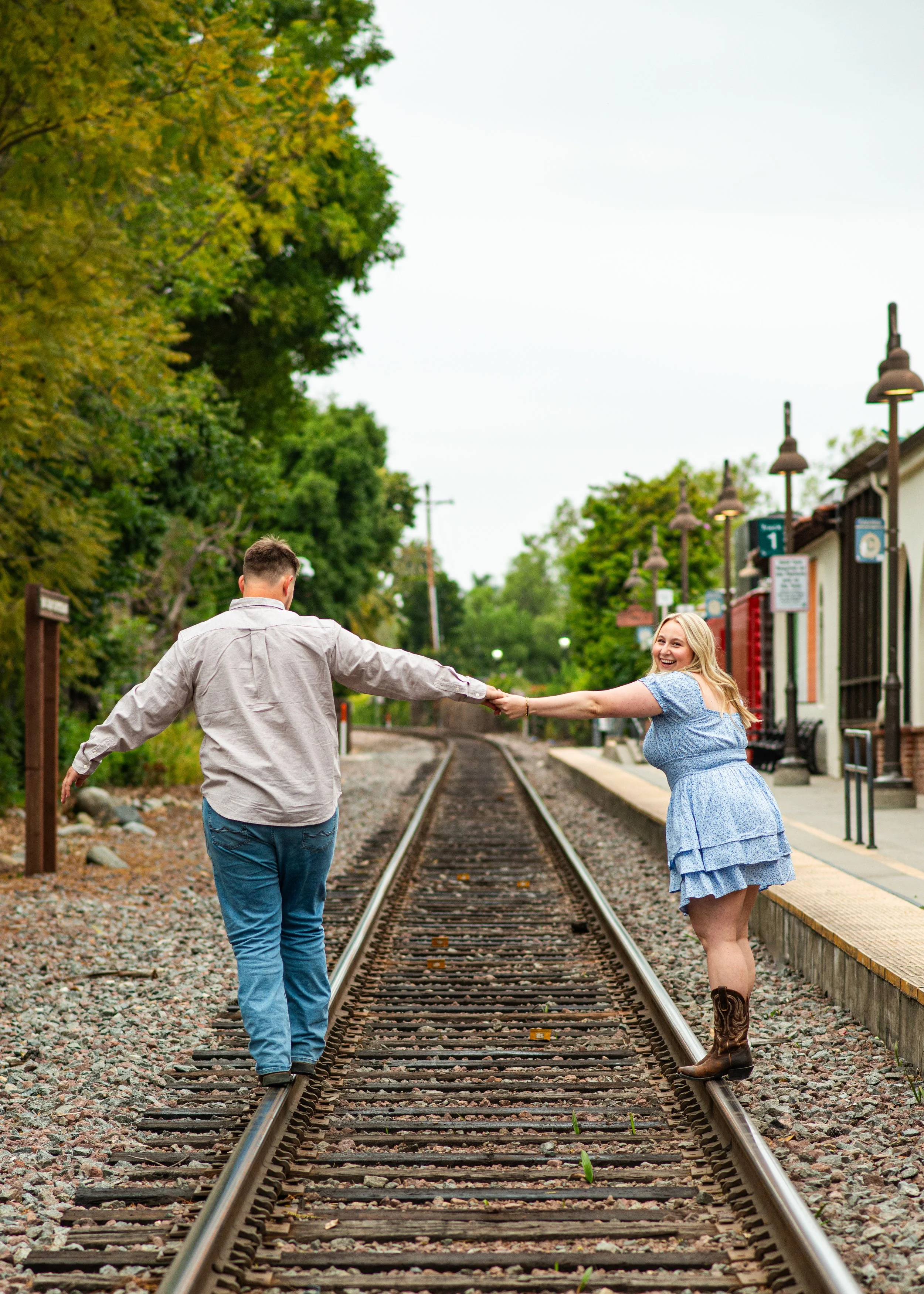 Cute couple on train tracks near beach in San Juan, California by Charlie Ogden