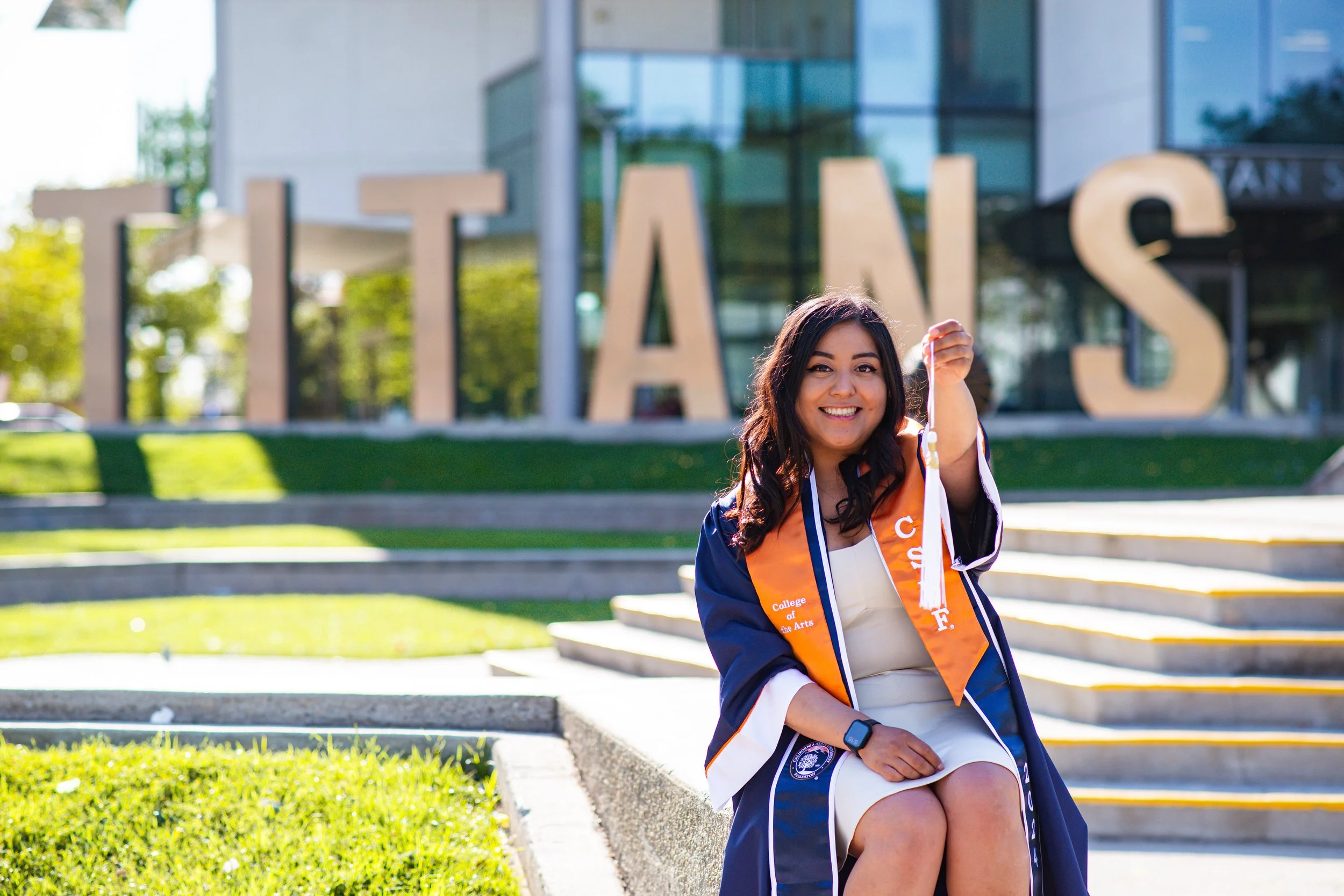Jenny holding graduation tassel in front of Titans sign at Cal State Fullerton 