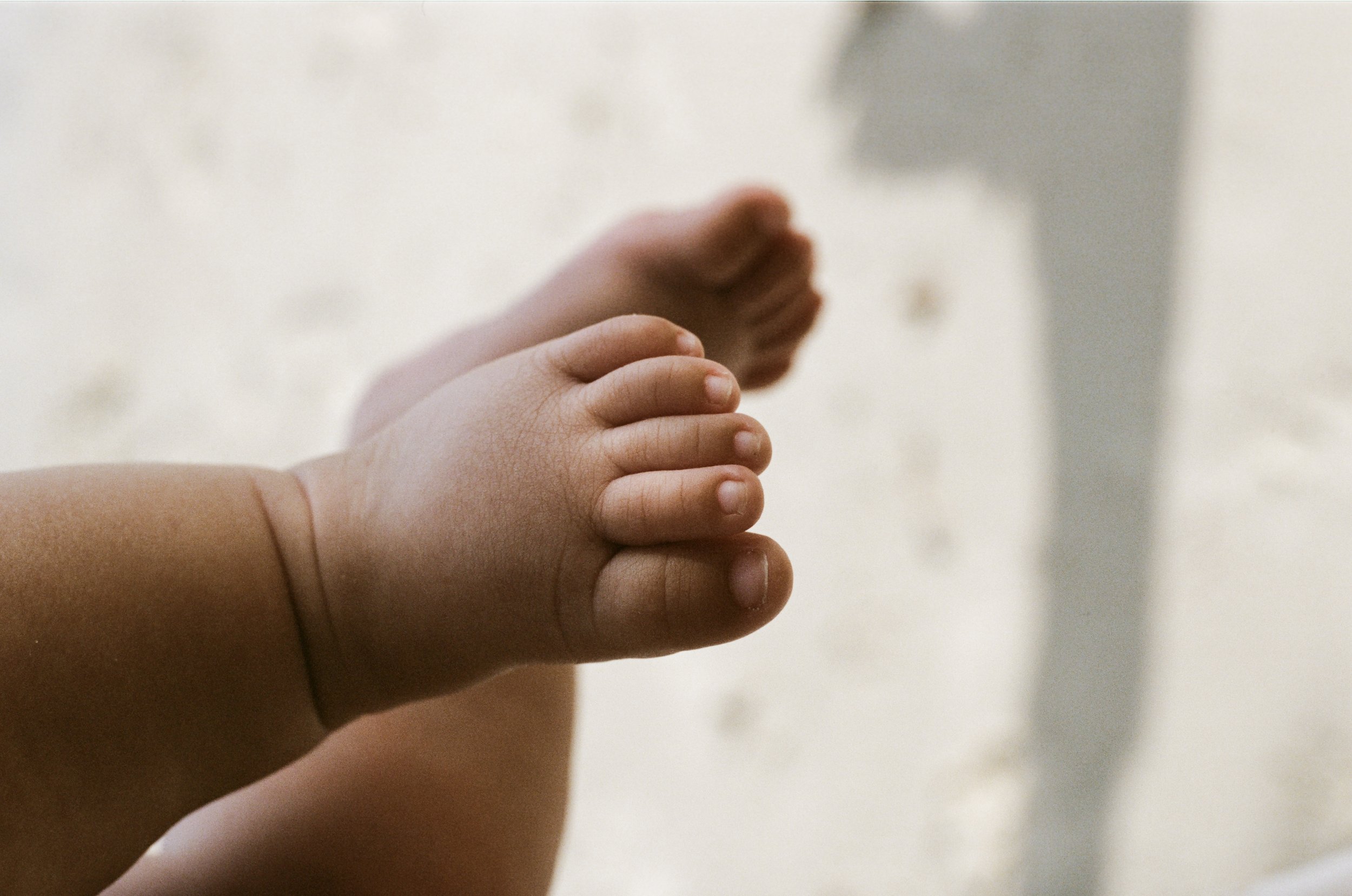 Close-up of a child's hand and an adult's hand reaching out to touch or hold each other, with a blurred background.