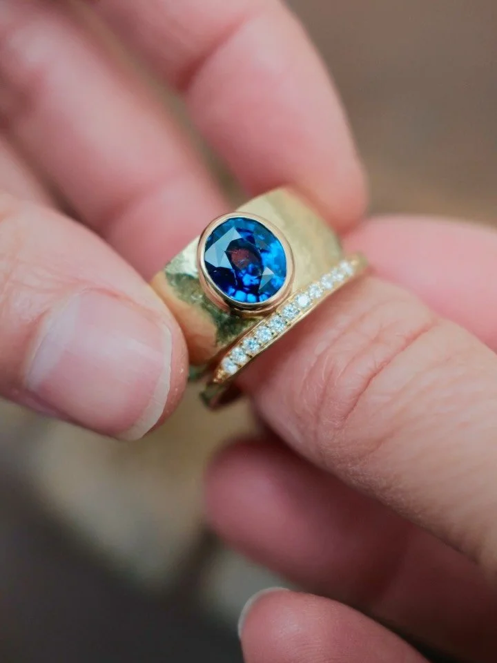 Jewellery Remodelling | 18ct Gold Cigar Band &amp; Diamond Ember ring 

A mesmerising blue sapphire remodelled from a clients preloved ring (see next slide), reset onto this gorgeous hand-forged yellow gold band to maximise the colour and beauty of t