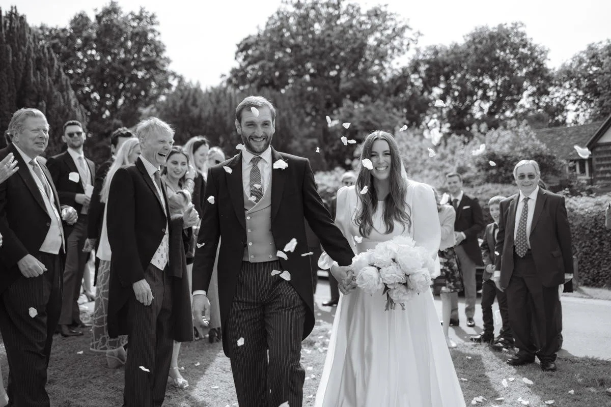 Couple going through a confetti tunnell after just getting married in church in Kent