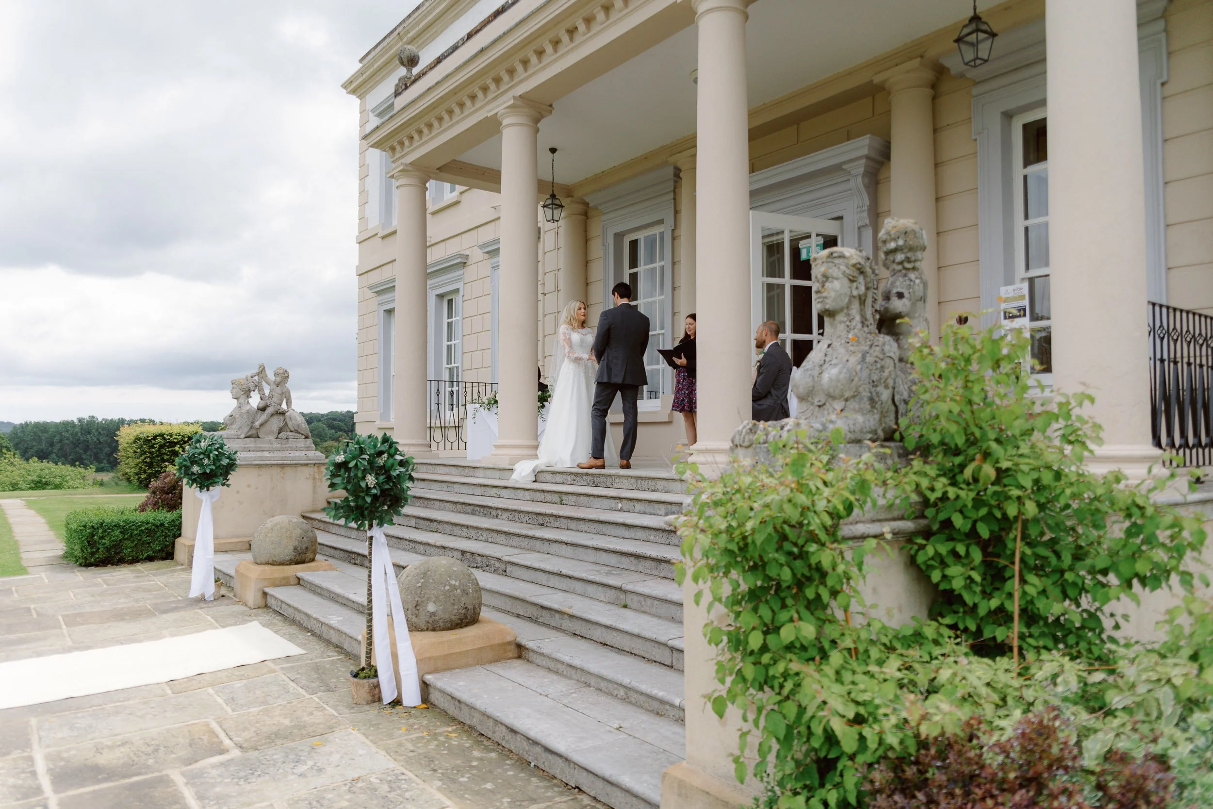 Couple getting married on the steps of a manor house at Buxted park