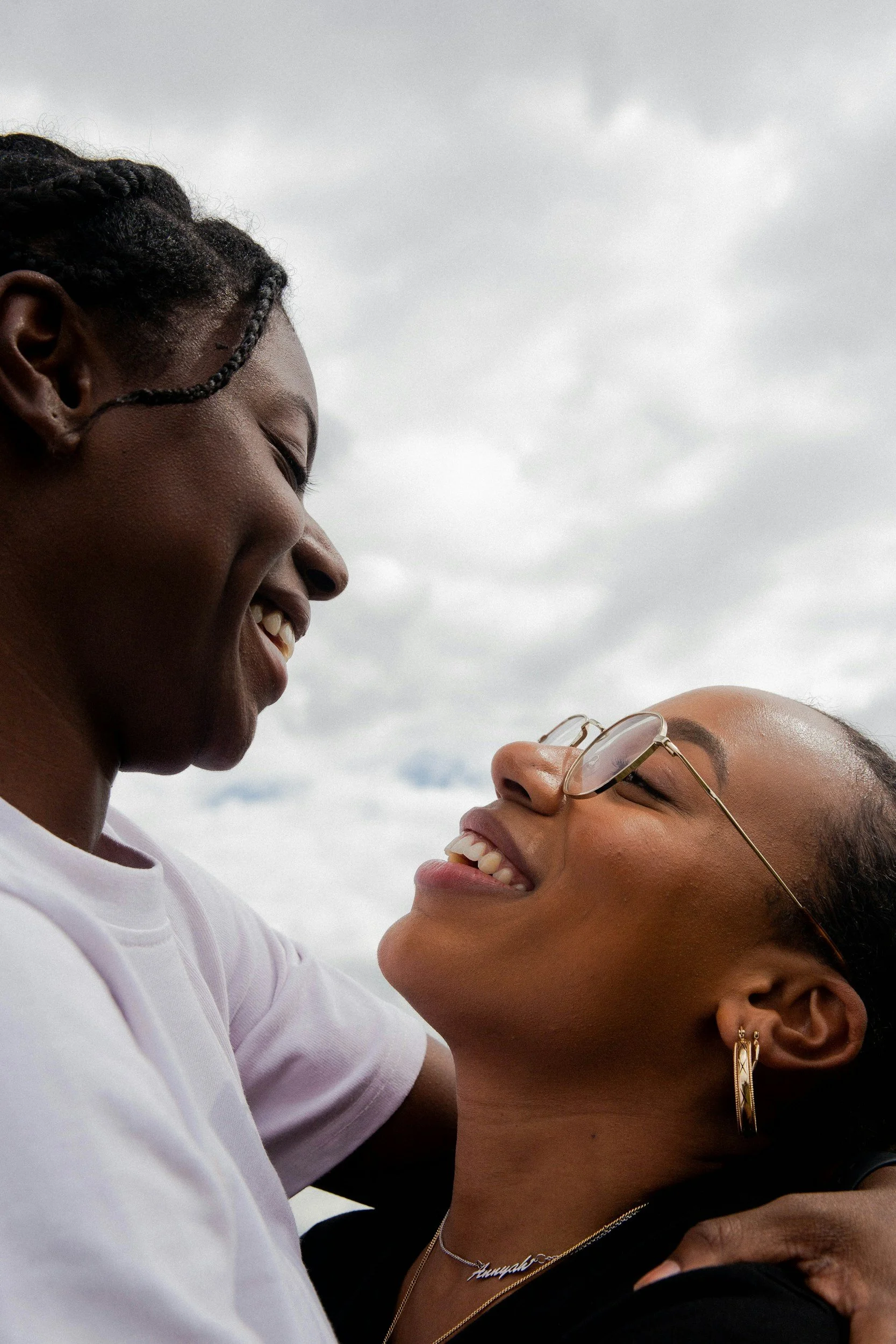 Black queer couple holding each other and smiling warmly at each other
