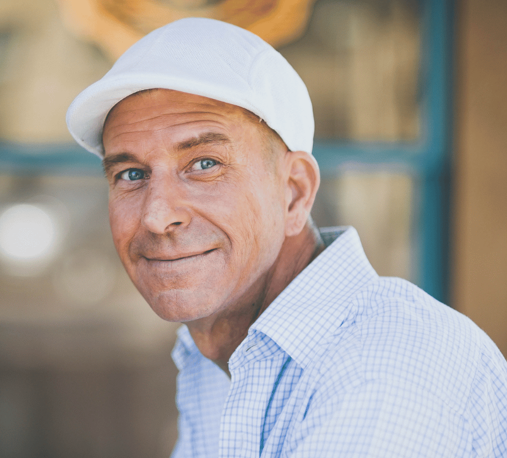 Smiling man with a white hat and blue checked shirt smiling
