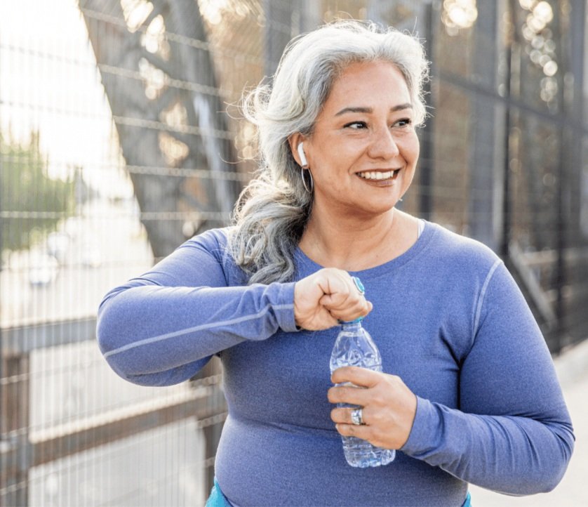 Woman drinking water bottle on a bridge