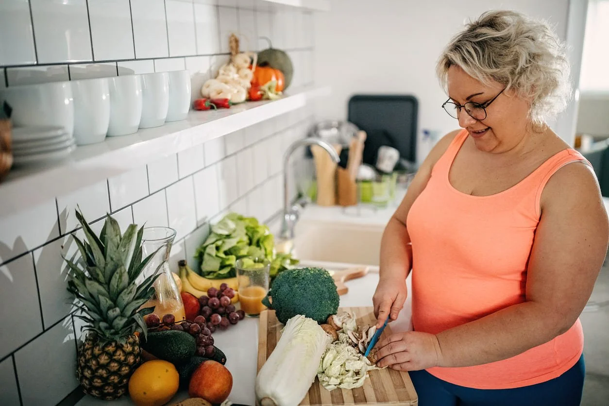 Woman in tank top preparing fruits and vegetables in the kitchen