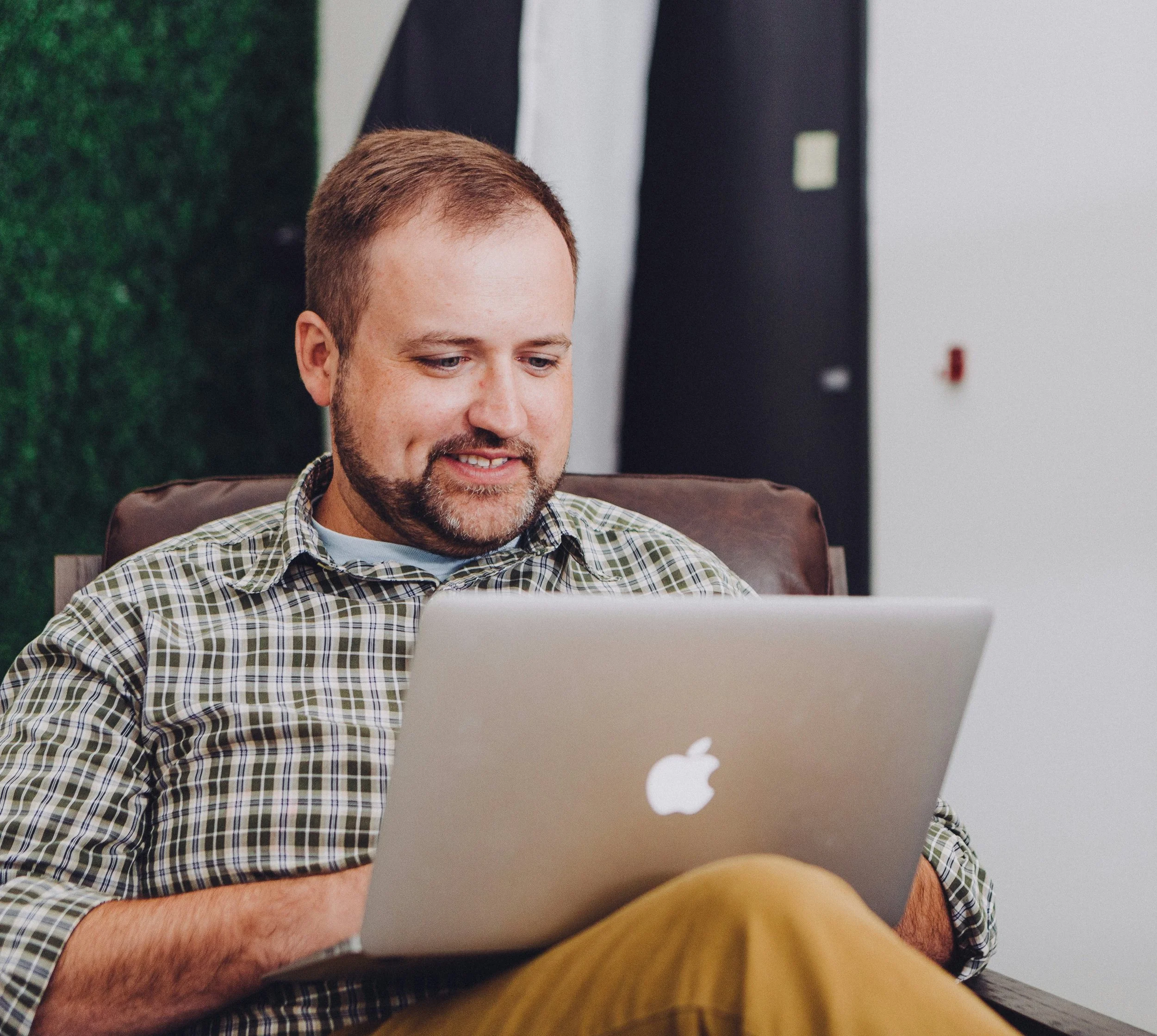 white man with beard looking at laptop in a chair