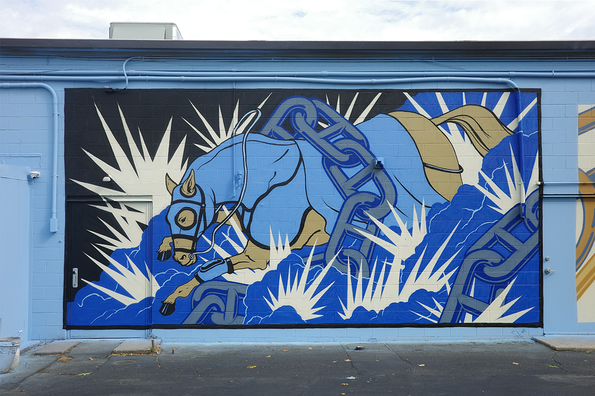 Fresque murale de street art par Shane Hello peinte sur un mur de bâtiment bleu ciel. L'œuvre représente un cheval bleu et beige équipé d'illoières, bondissant au travers de maillons de chaînes métalliques et d'éclats graphiques blancs. La scène dyna