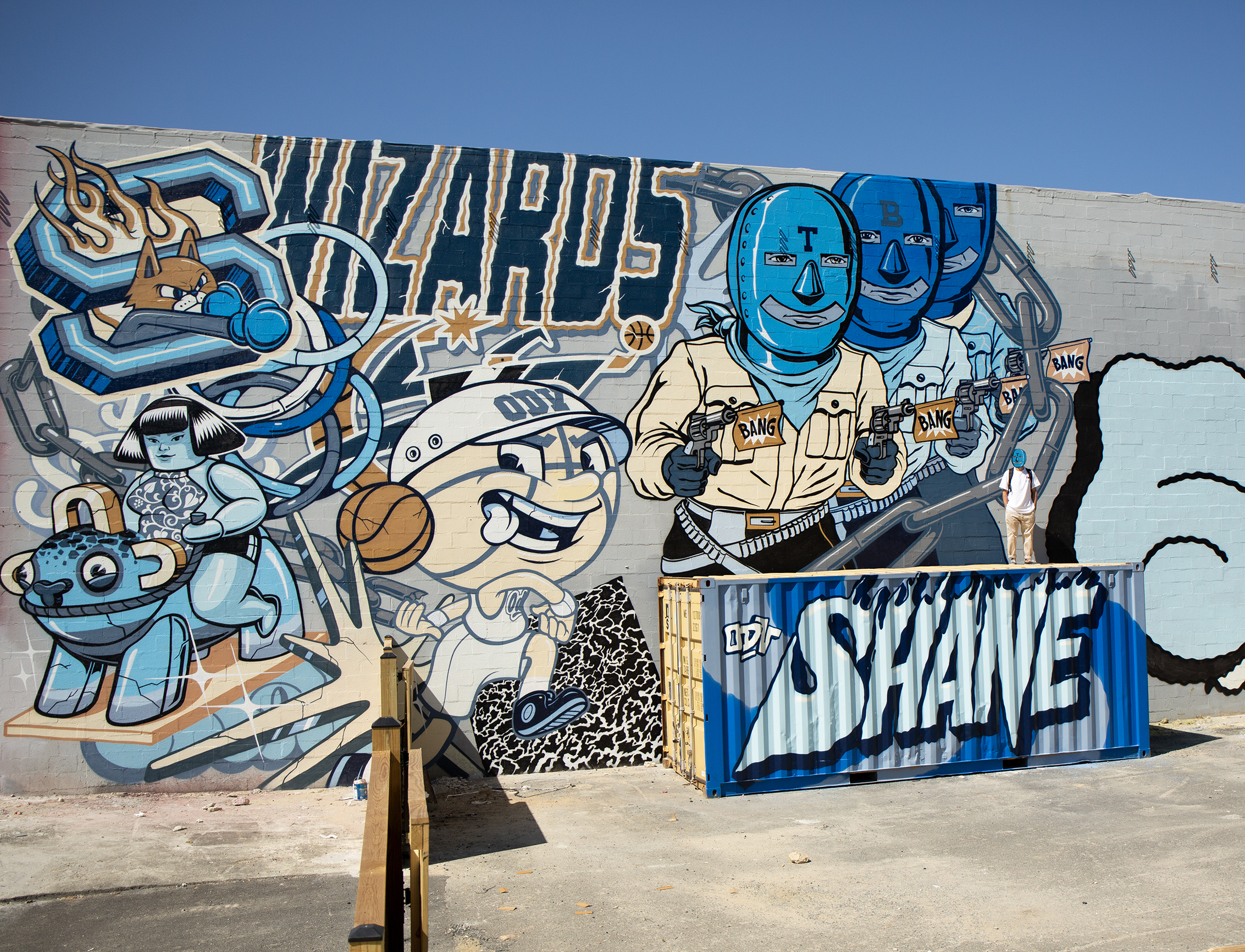 Immense fresque murale street art à Washington réalisée par l'artiste Shane Hello. L'œuvre aux tons bleus intègre le lettrage « WIZARDS » en référence à l'équipe de NBA, divers personnages de bandes dessinées et mascottes de baseball, ainsi que trois