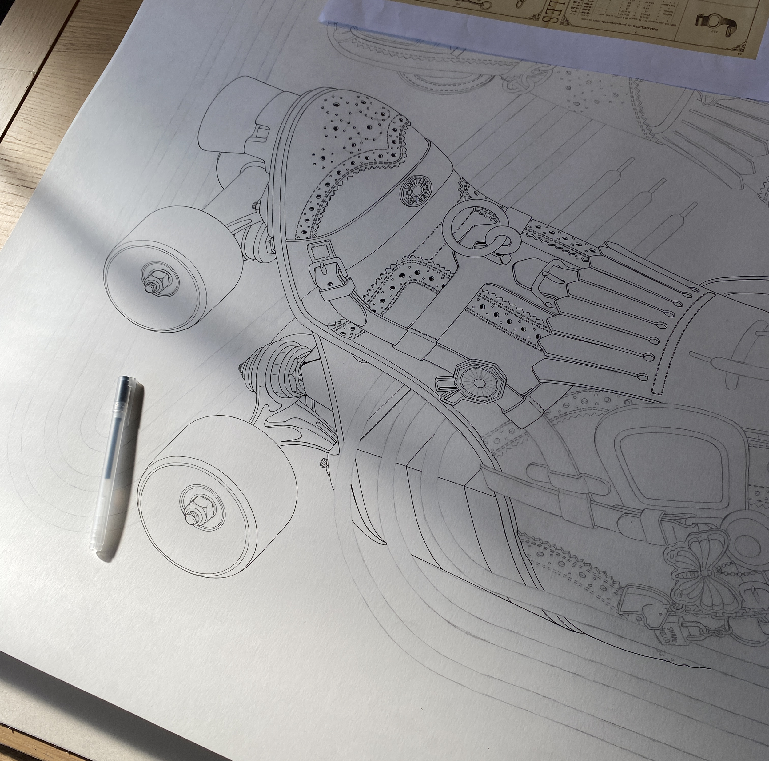 Vue en plongée de l'illustration originale au trait sur papier grand format pour le carré Hermès "Derby 2000", dessinée à l'encre noire par Shane hello avec un stylo de précision posé à côté.