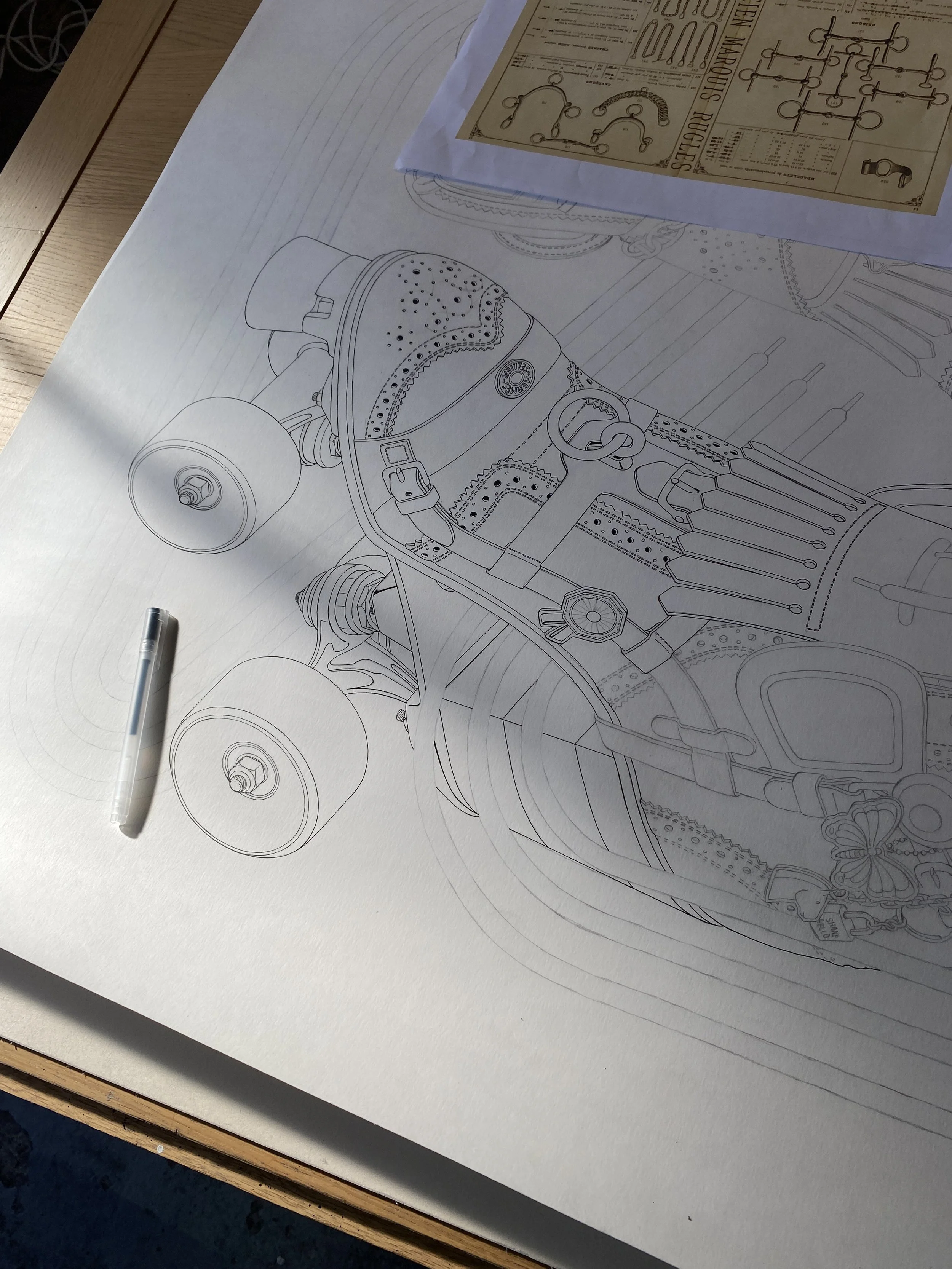 Cette photographie en plongée montre une étape de travail en cours (Work in Progress) sur une table en bois. Au centre, un grand dessin original réalisé à l'encre noire sur du papier d'art blanc dévoile les contours minutieux d'un patin à roulettes r