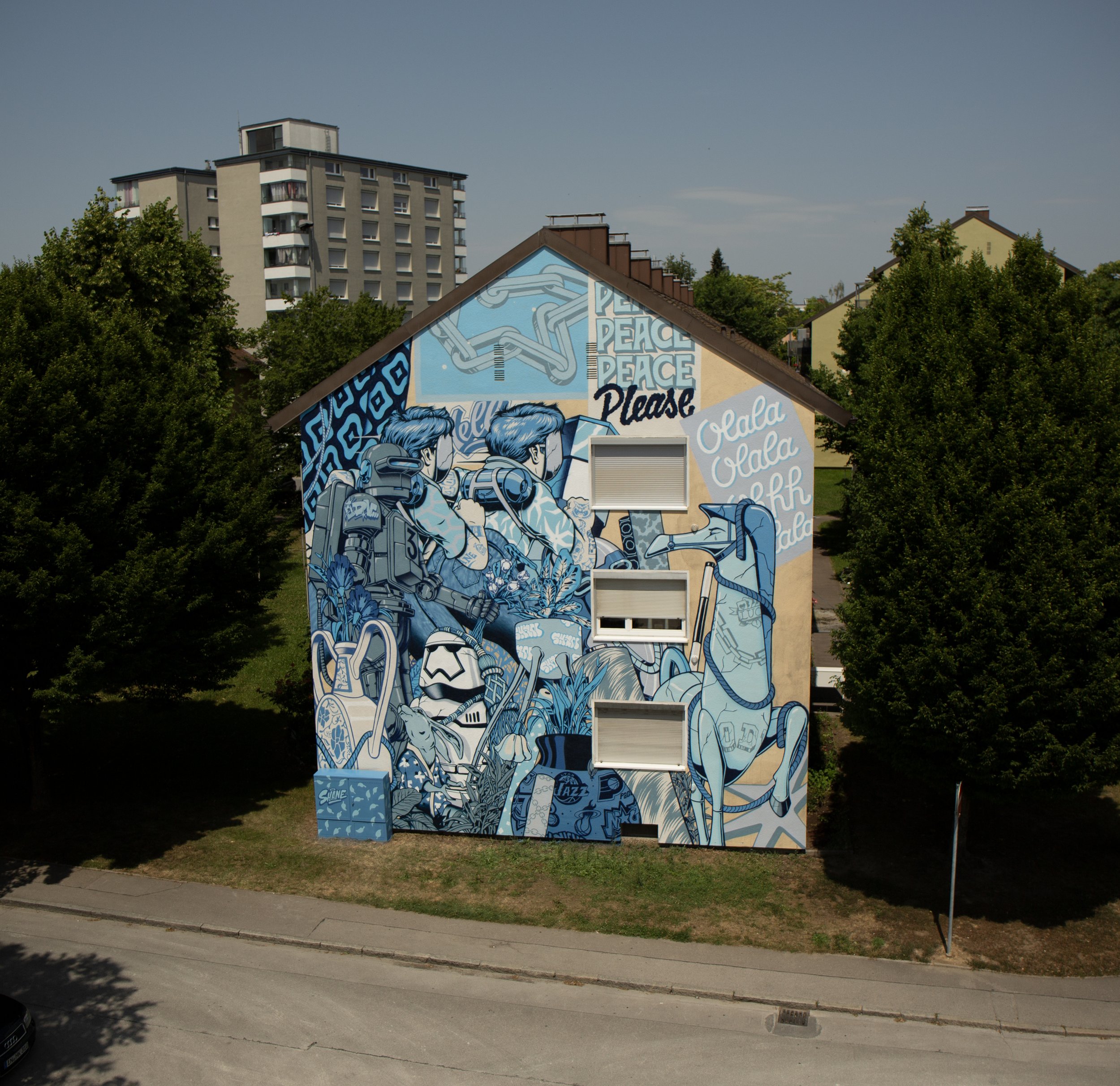 Gros plan sur une murale graffiti bleue sur la façade d'un immeuble d'habitation. Le fichier Murale_graffiti_blue_bleu.jpg_2.jpg montre un mélange complexe de personnages, d'animaux, de plantes et de messages."