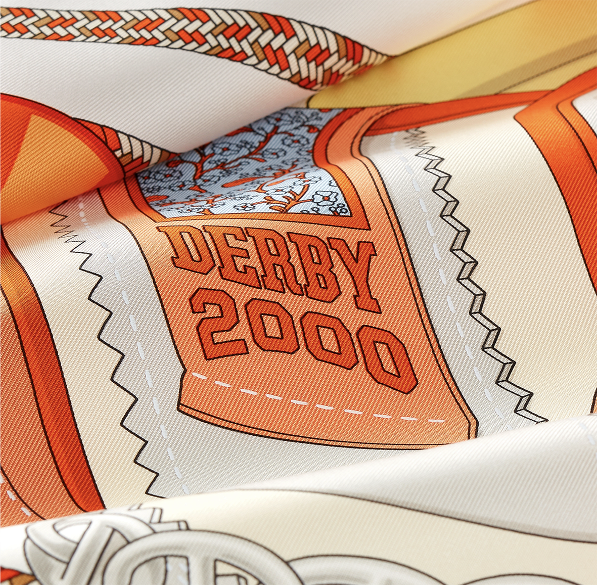 Gros plan détaillé sur le motif sérigraphié "DERBY 2000" d'un foulard en soie Hermès de Shane hello, montrant la texture du tissu et les détails précis de l'illustration graphique orange et bleu ciel d'une patinette de roller derby.