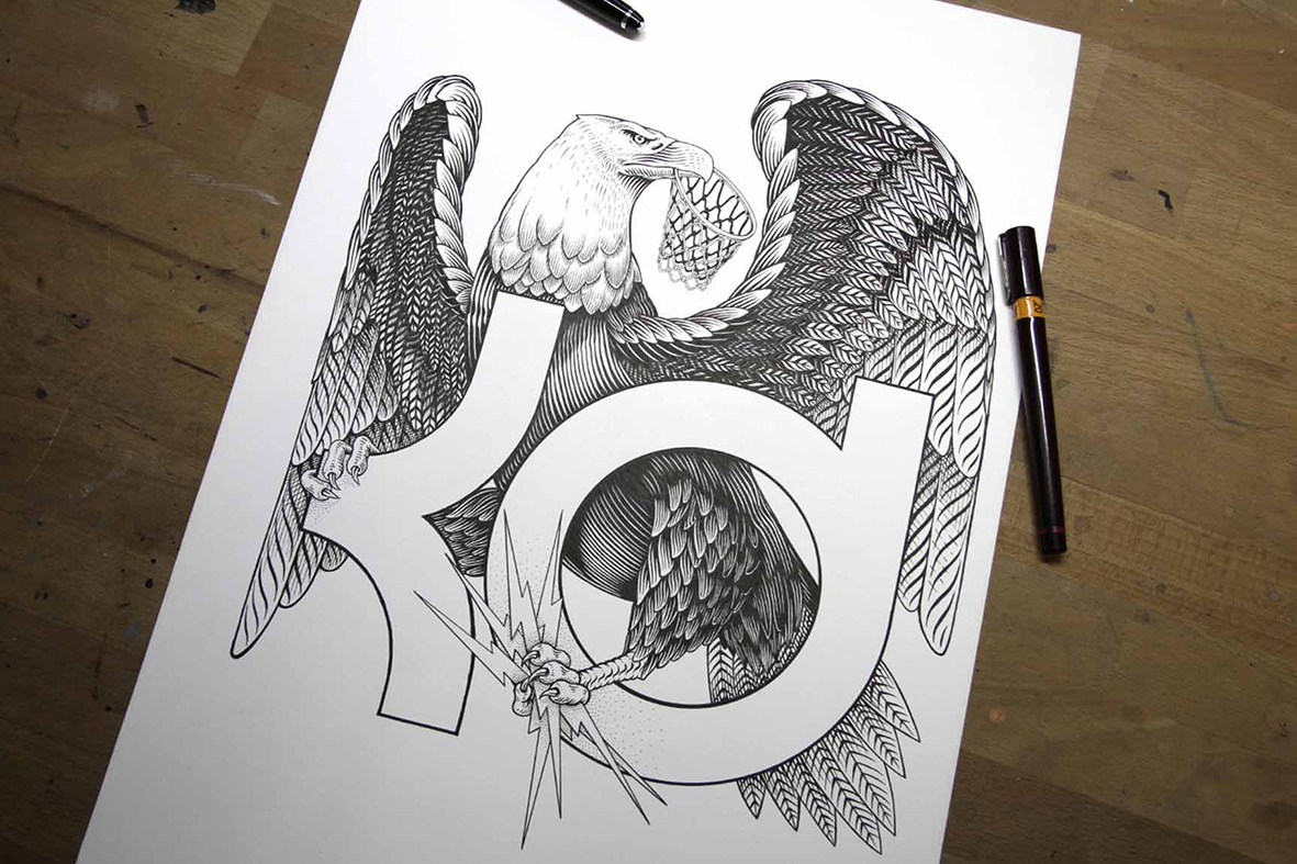 Dessin original sur papier posé sur une table en bois avec des feutres fins à côté. L'illustration réalisée par Shane Hello en noir et blanc représente le logo KD de Kevin Durant entrelacé avec un aigle aux ailes déployées, saisissant des éclairs dan