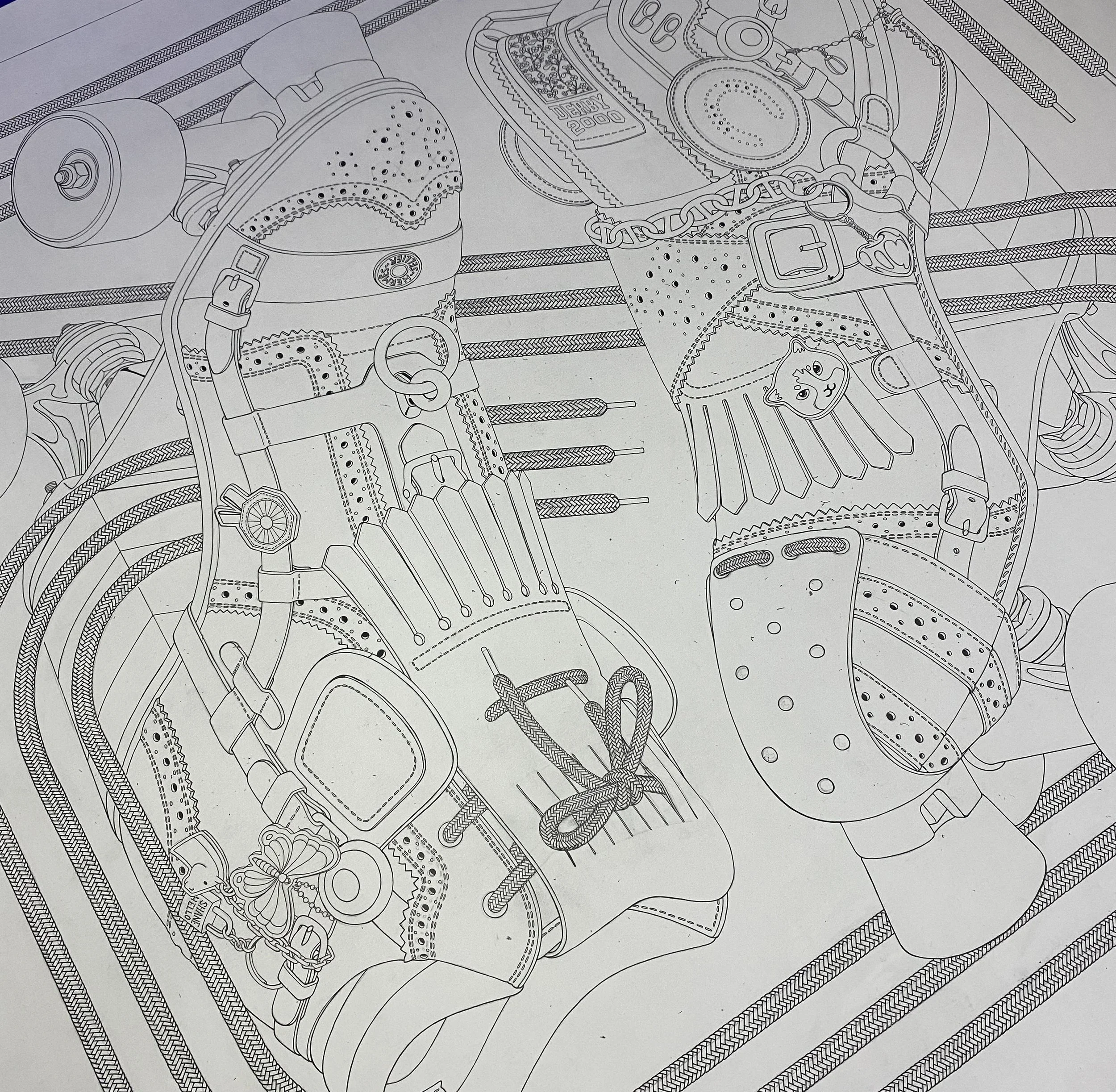 Cette photographie en plongée montre une étape de travail en cours (Work in Progress) sur une table en bois. Au centre, un grand dessin original réalisé à l'encre noire sur du papier d'art blanc dévoile les contours minutieux d'un patin à roulettes r