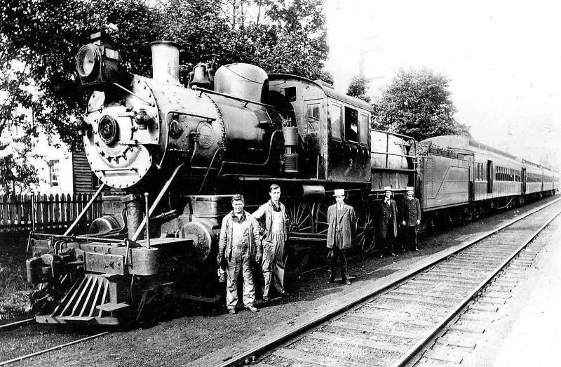 A 1912 image of LIRR workers in dirty clothes in front of a steam engine.