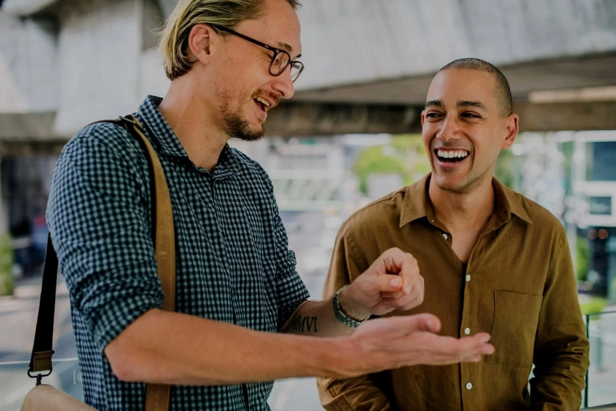 Two men engaging in conversation, smiling, indoors in a bright space.