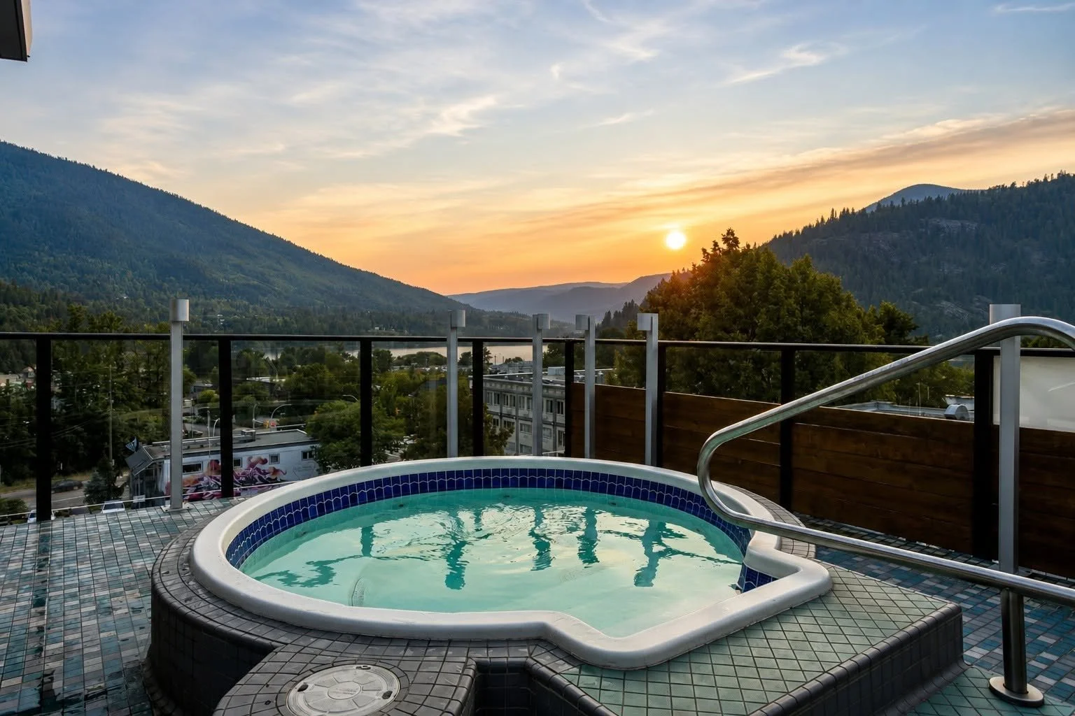 A rooftop hot tub overlooks Kootenay Lake in Nelson BC during a golden sunset.