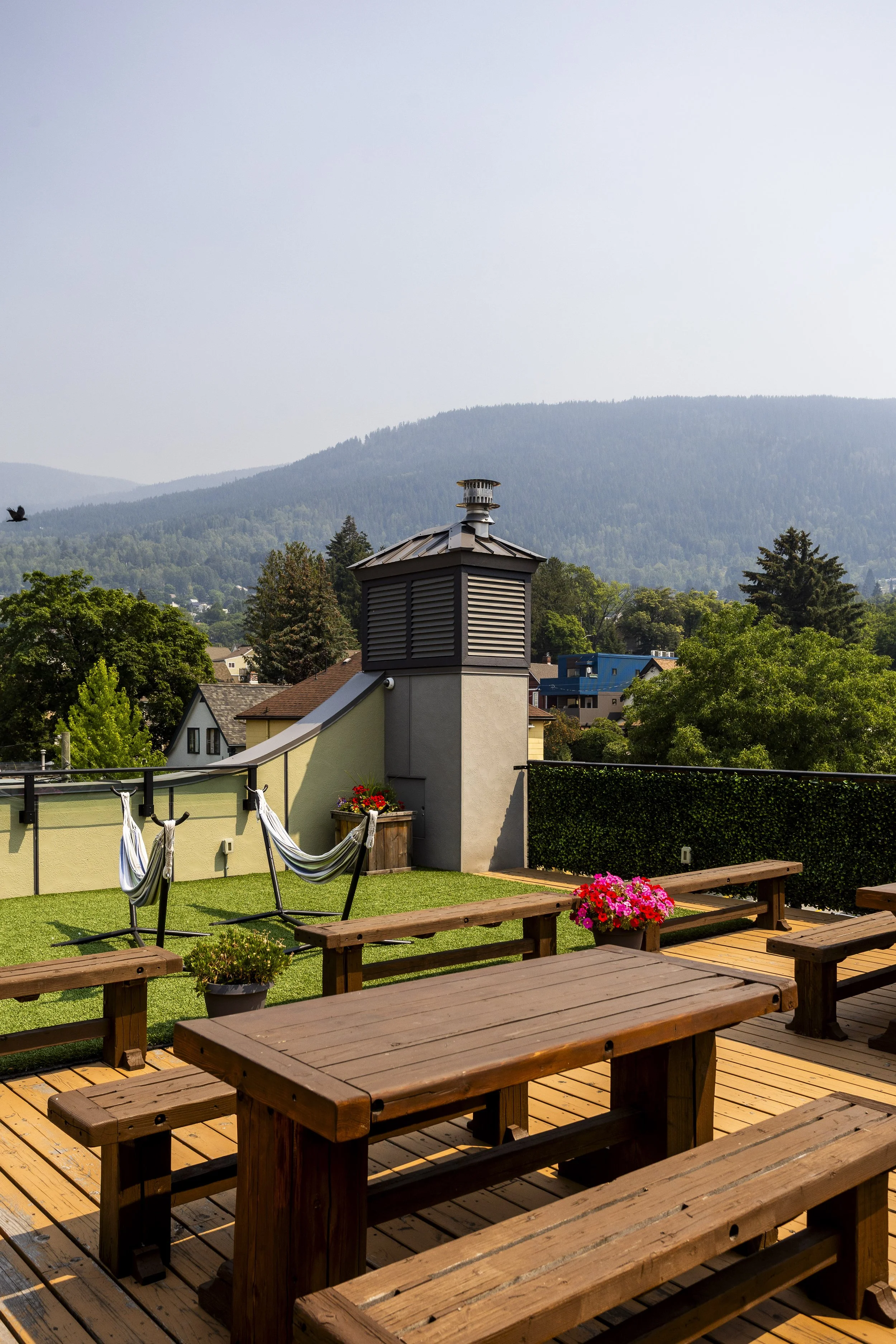 A rooftop patio invites guests to come enjoy picnic tables and hammocks along with green grassy turf.