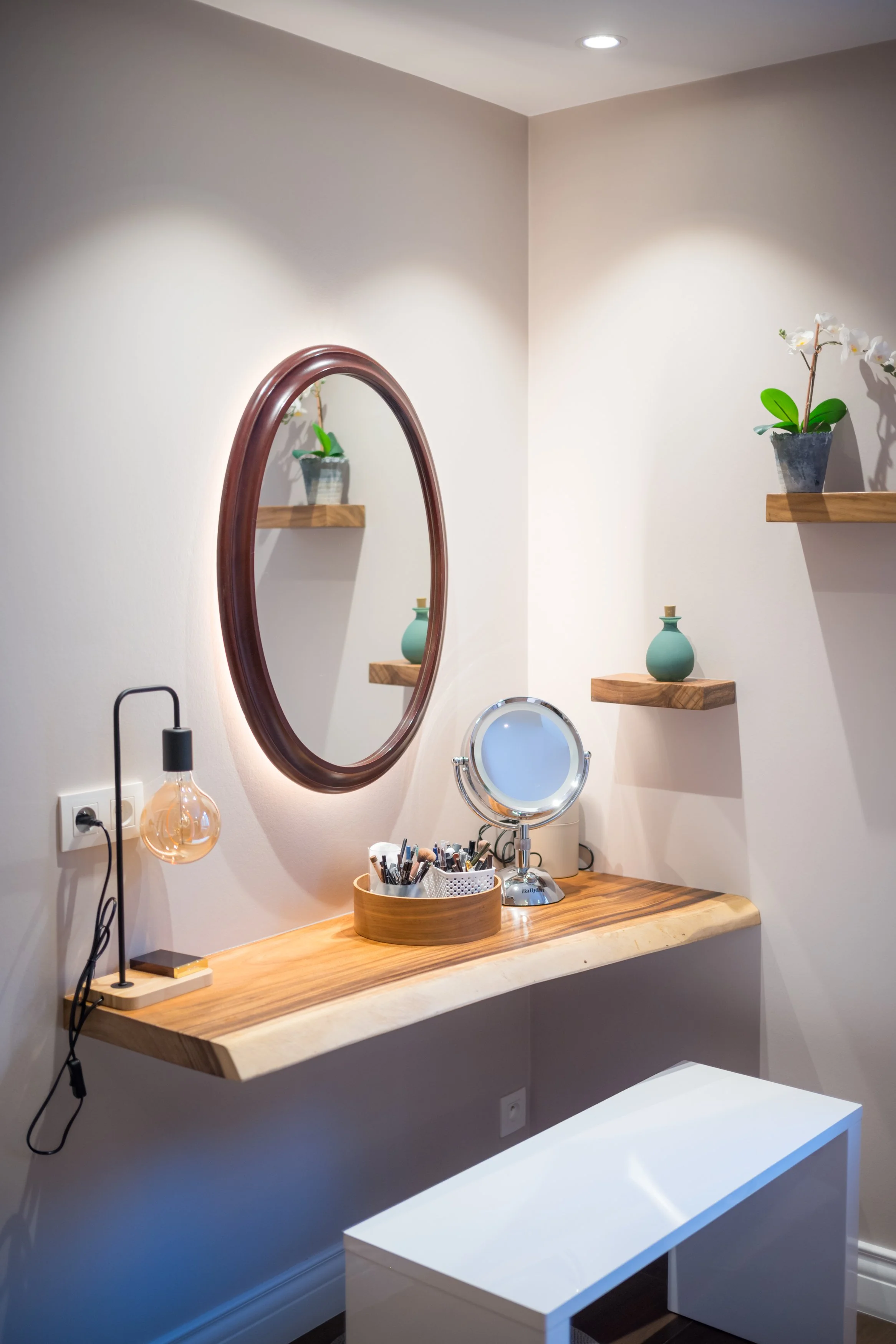 Een verfijnde dames make-up plek met een houten tafel, een ronde spiegel, een spiegel met lamp, en decoratieve potten met bloemen