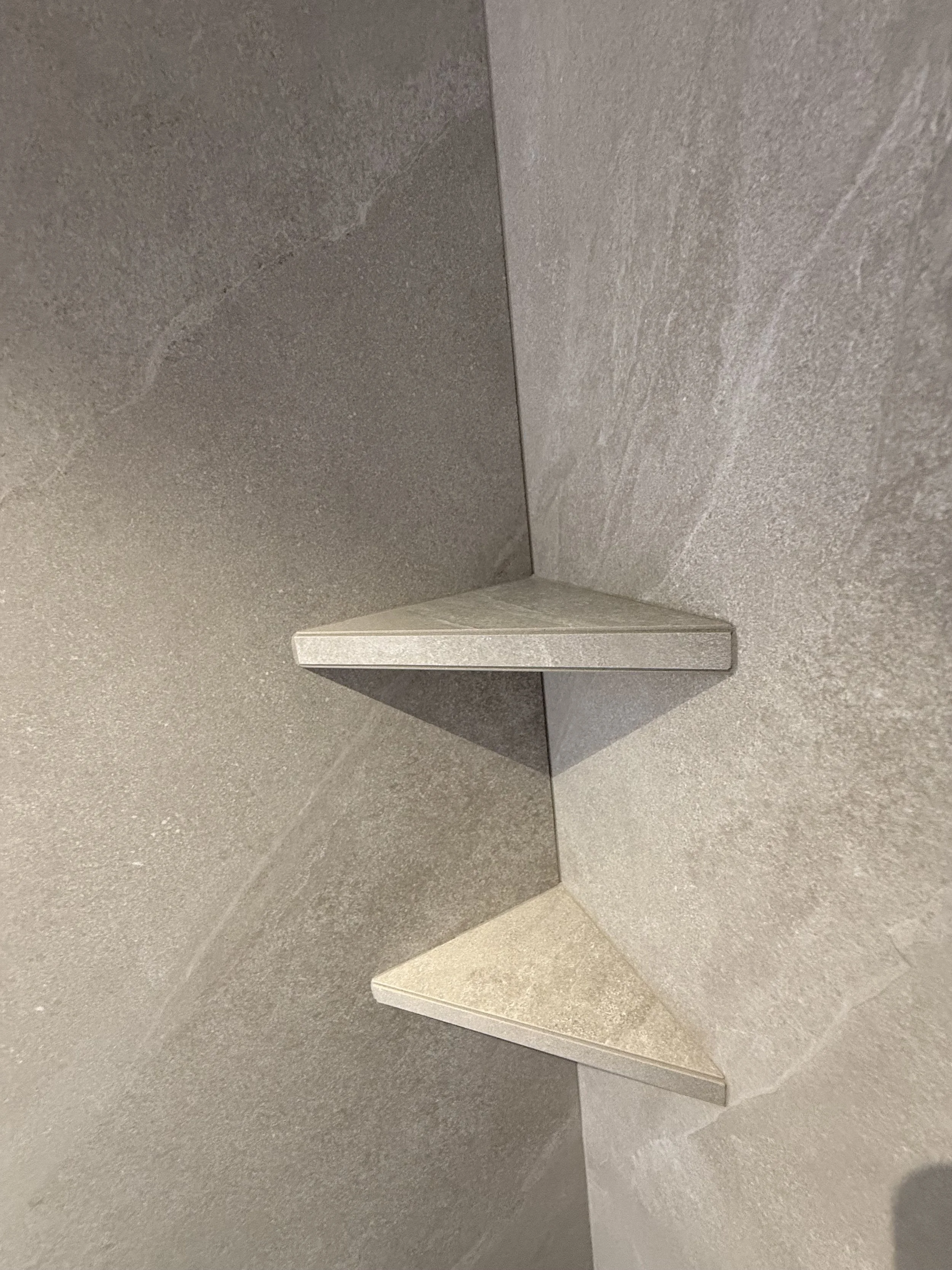 Twee hoekplanken bevestigd aan een muur met tegels, één plank boven de andere.