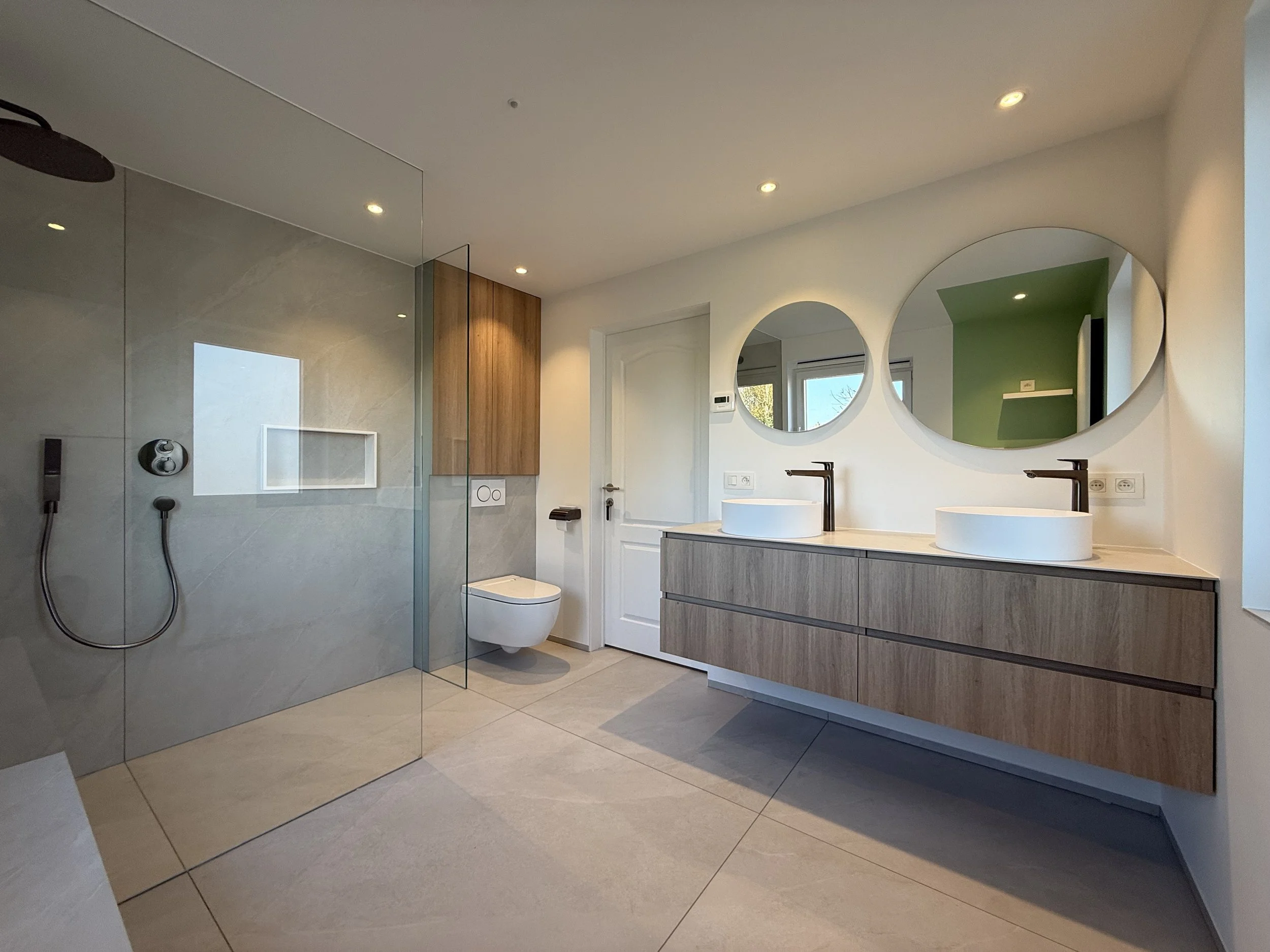 Moderne badkamer met verdeling in douchegedeelte en wastafel met dubbele spiegels.