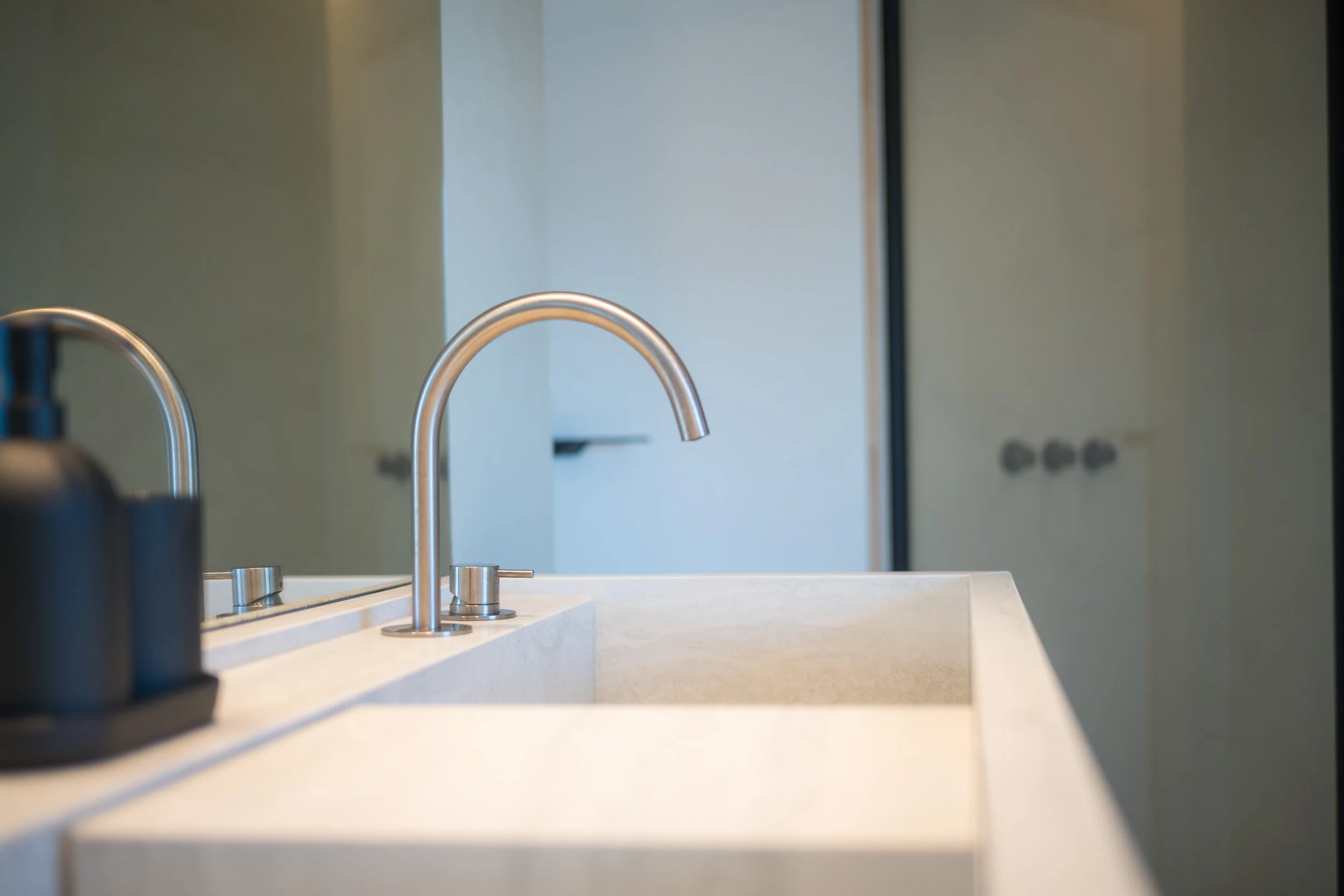 Moderne keuken met wit werkblad en dubbel spateltje, in de achtergrond een muur met lichtblauwe kleur.