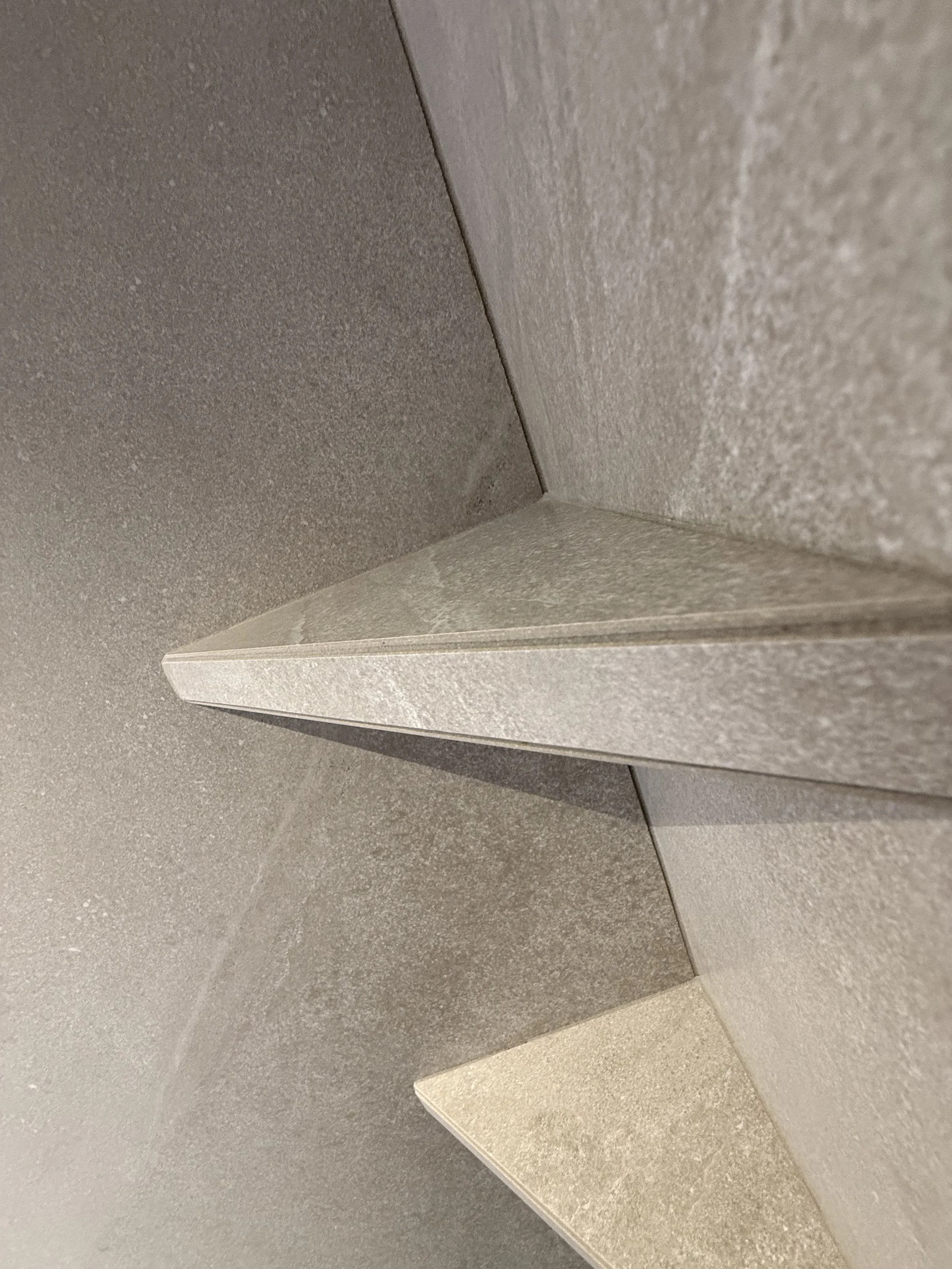 Close-up van een hoek met gelaagde, gestucte muren en plafond, in neutrale kleuren.