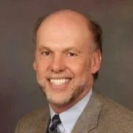 Headshot of Michael Dunn, a middle-aged man with facial hair who is wearing a jacket and tie and smiling at the camera