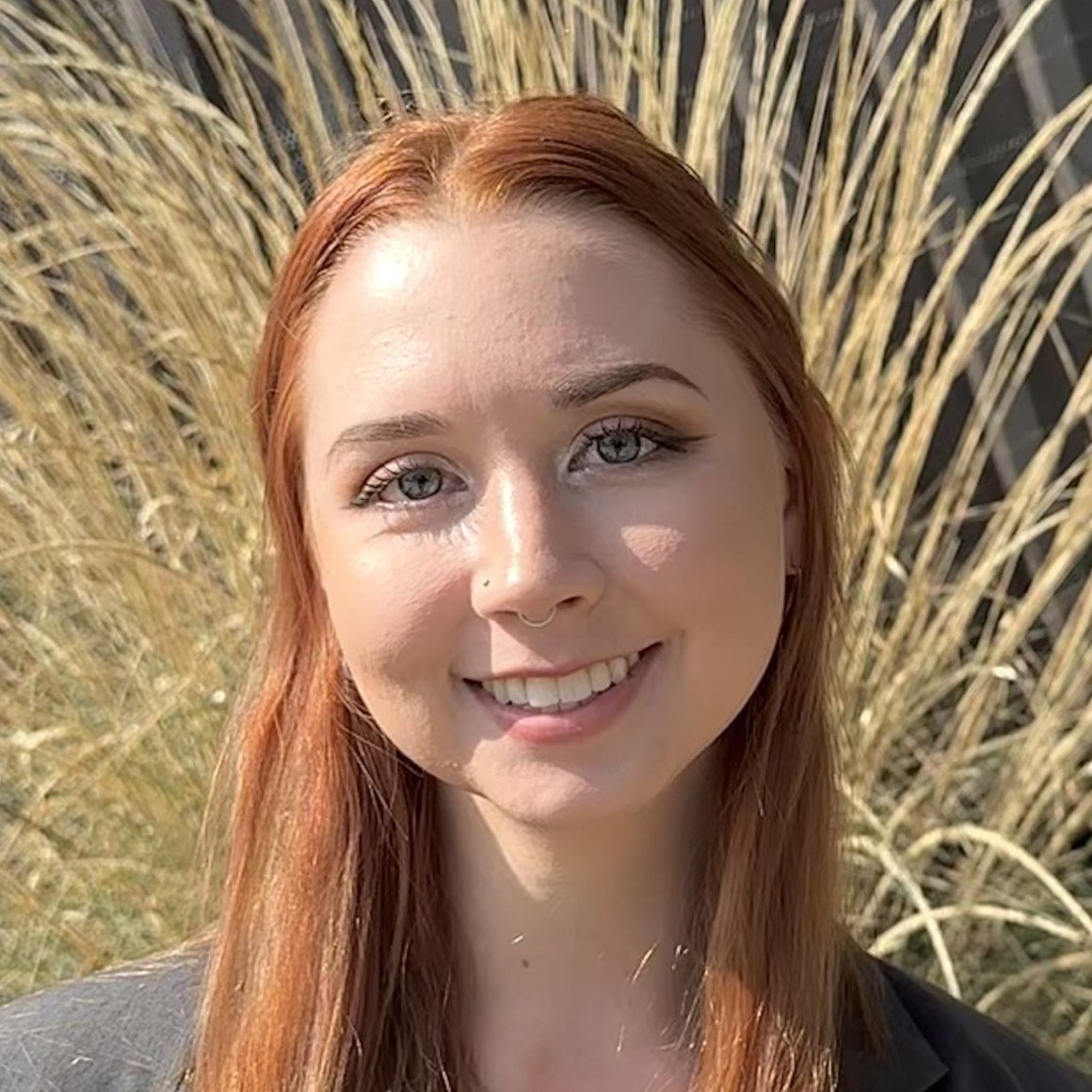 Tia is a young woman with long, straight reddish hair. She's smiling at the camera.