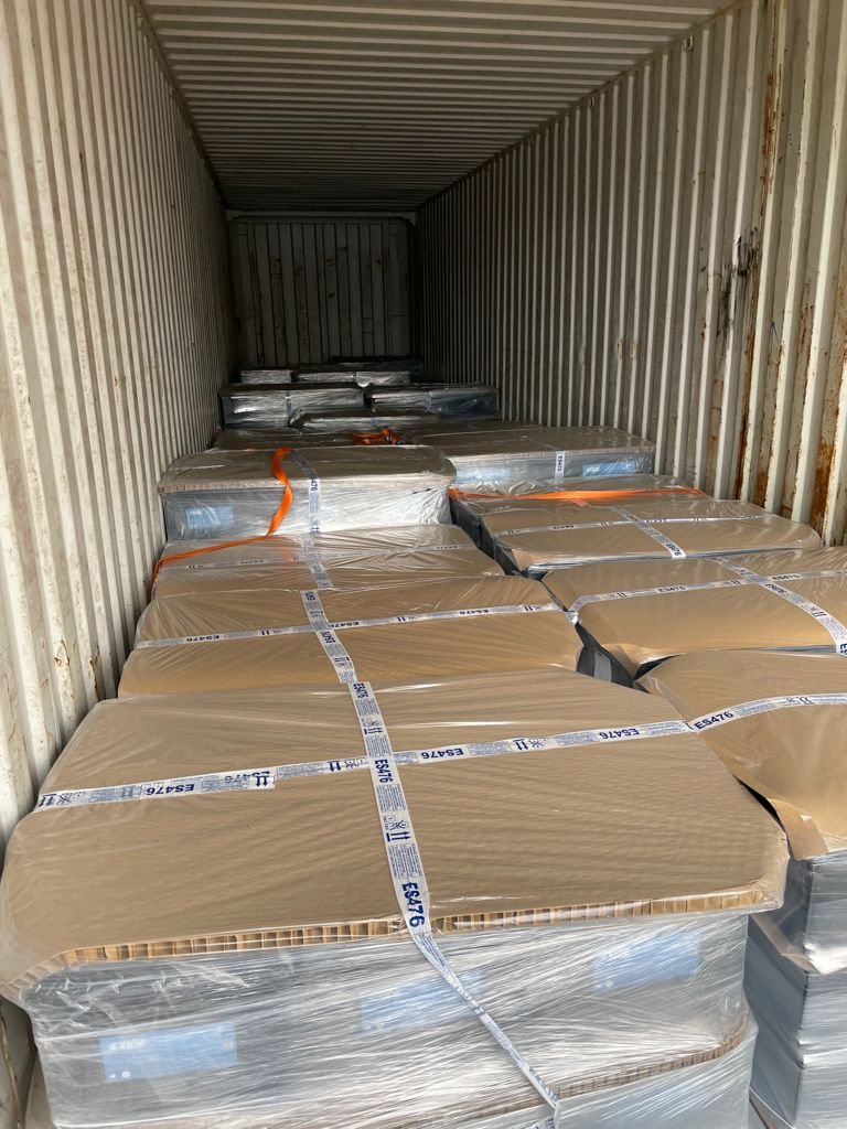 Stacked cardboard sheets inside a shipping container secured with straps.
