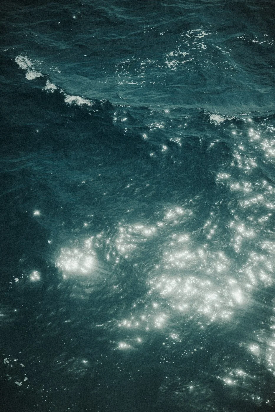 Sunlight glinting on the surface of dark turquoise ocean waves.jpg