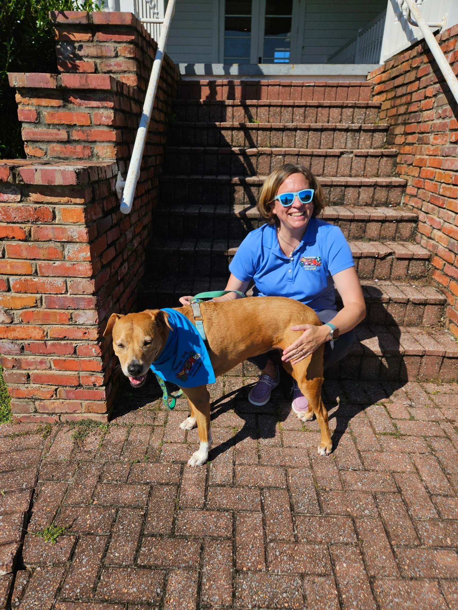 Photograph of Christie and Chloe on brick steps in Defuniak Springs, Fla., wearing matching Dog-Harmony blue-colored shirt and bandana respectively